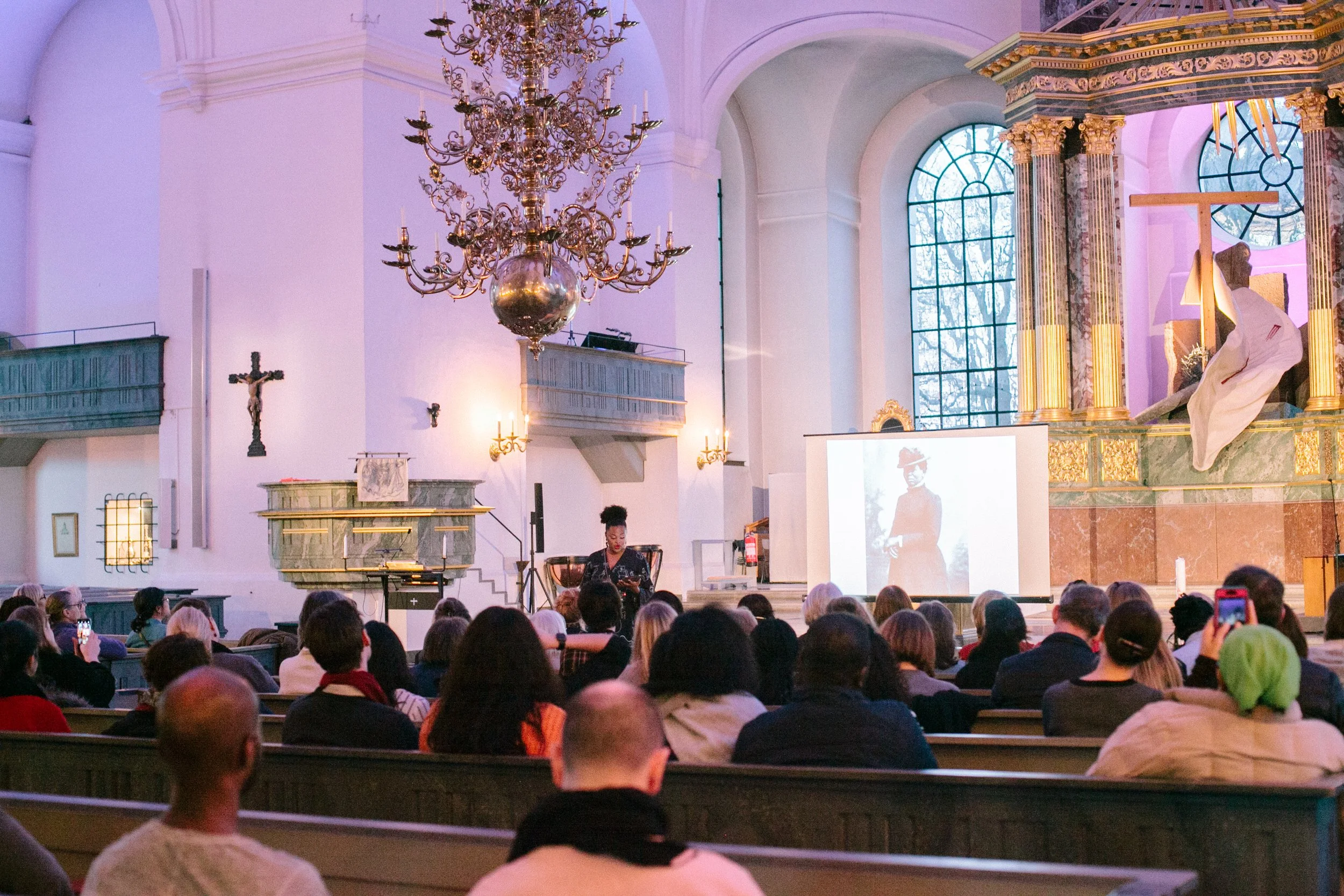 Föreläsning i kyrka med personer i kyrkbänkarna.