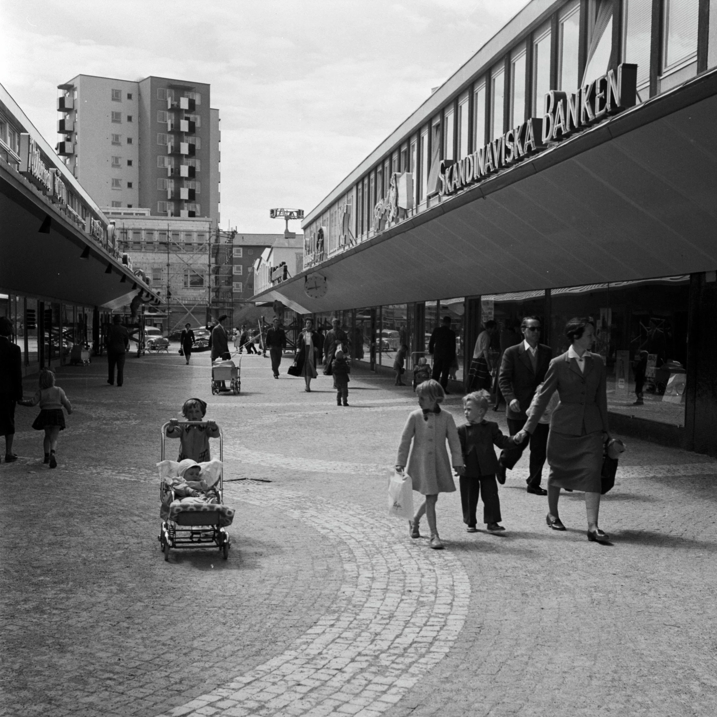 Barn och vuxna i Vällingby centrum, längst bort syns en byggnadsställning.