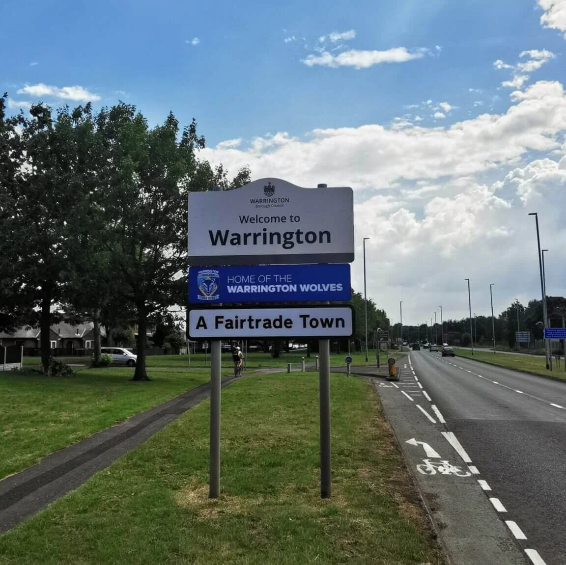 Photo showing Welcome to Warrington sign. Blue sky and fluffy clouds in the background.