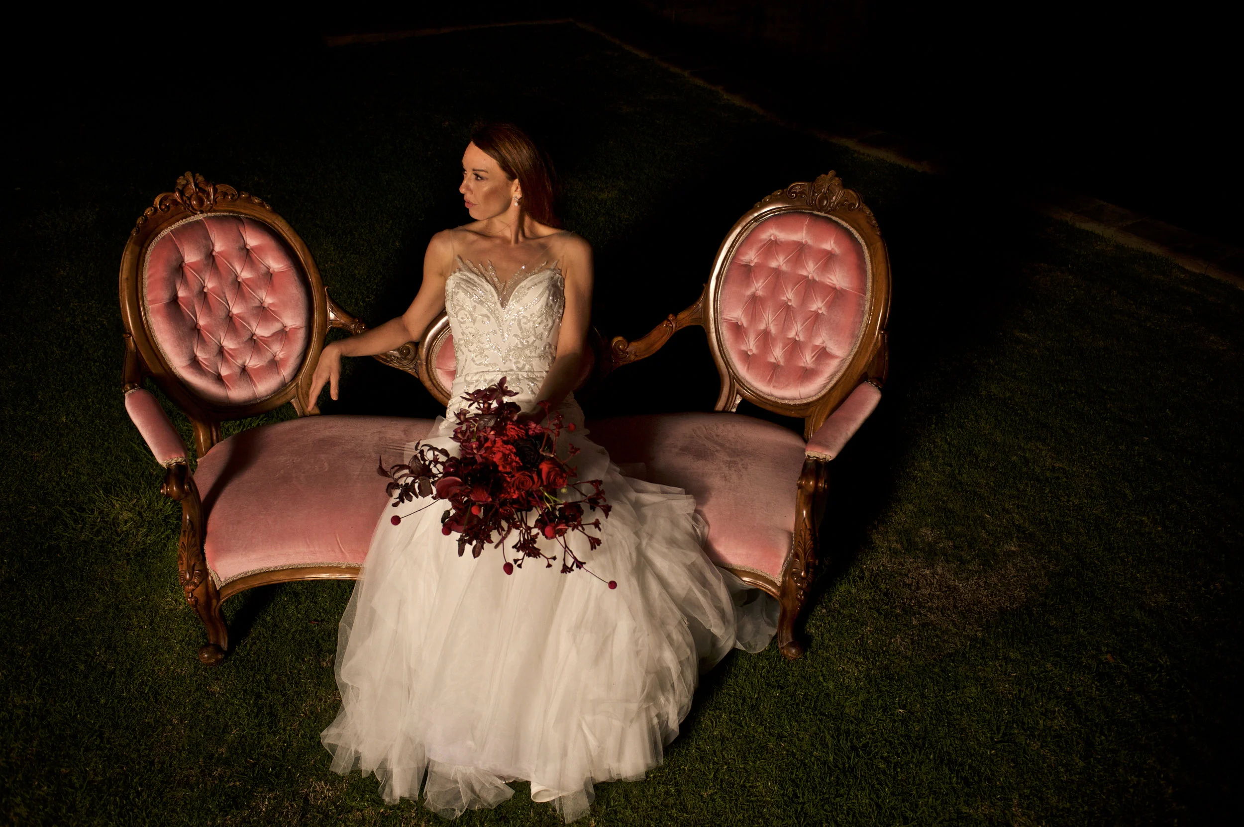 beautiful bride with flowers seated on a pink couch