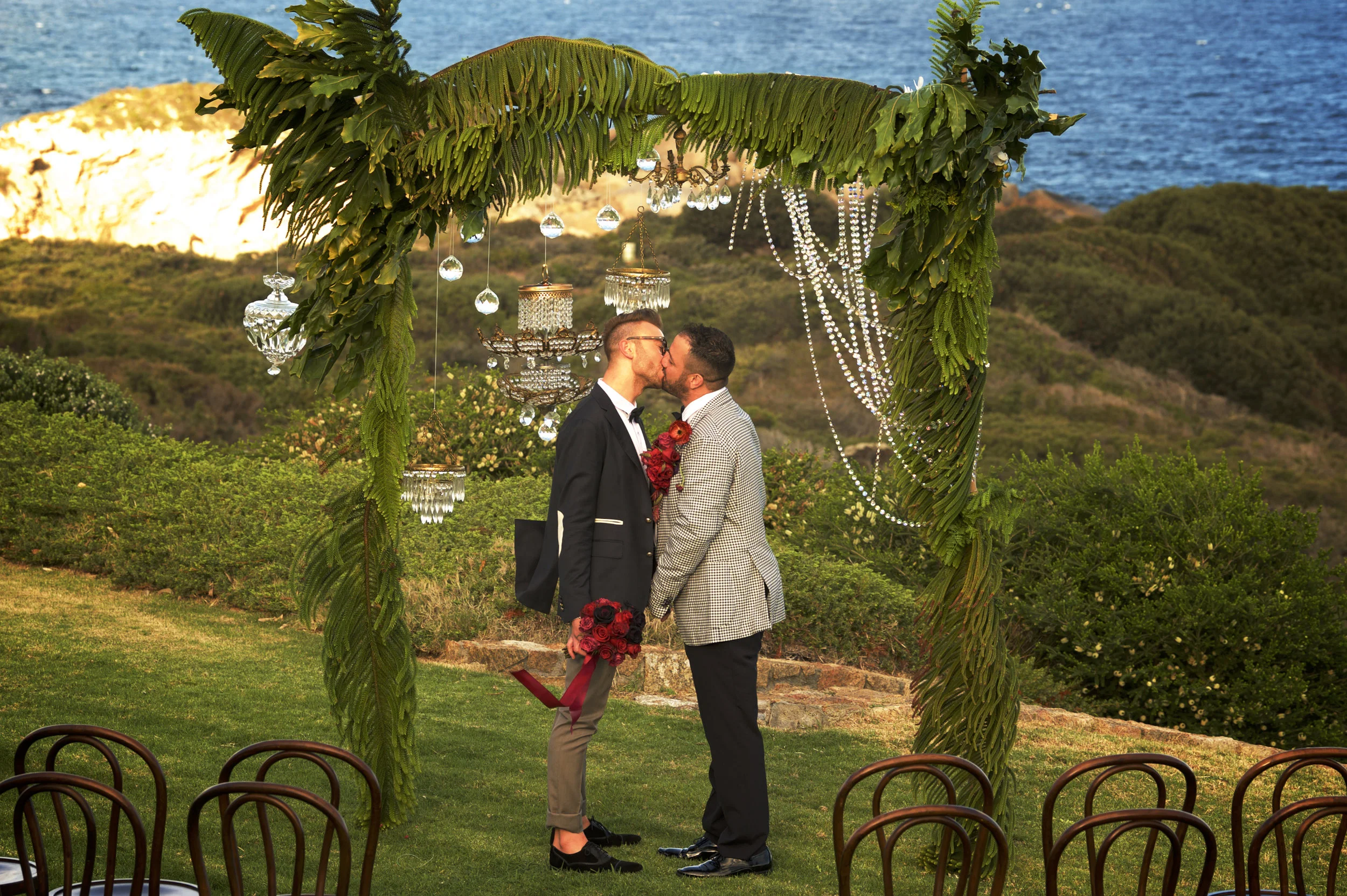 couple kissing under the altar with chairs and palm decorations