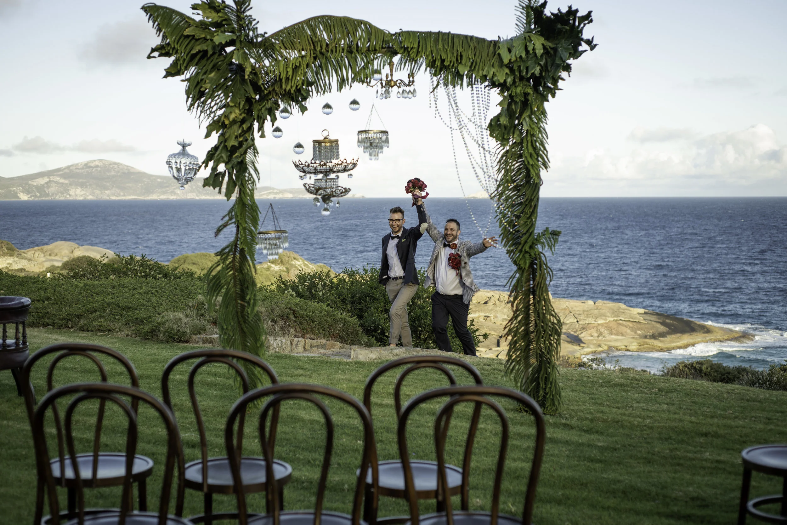 wedding couple under altar holding each other with flower bouquets