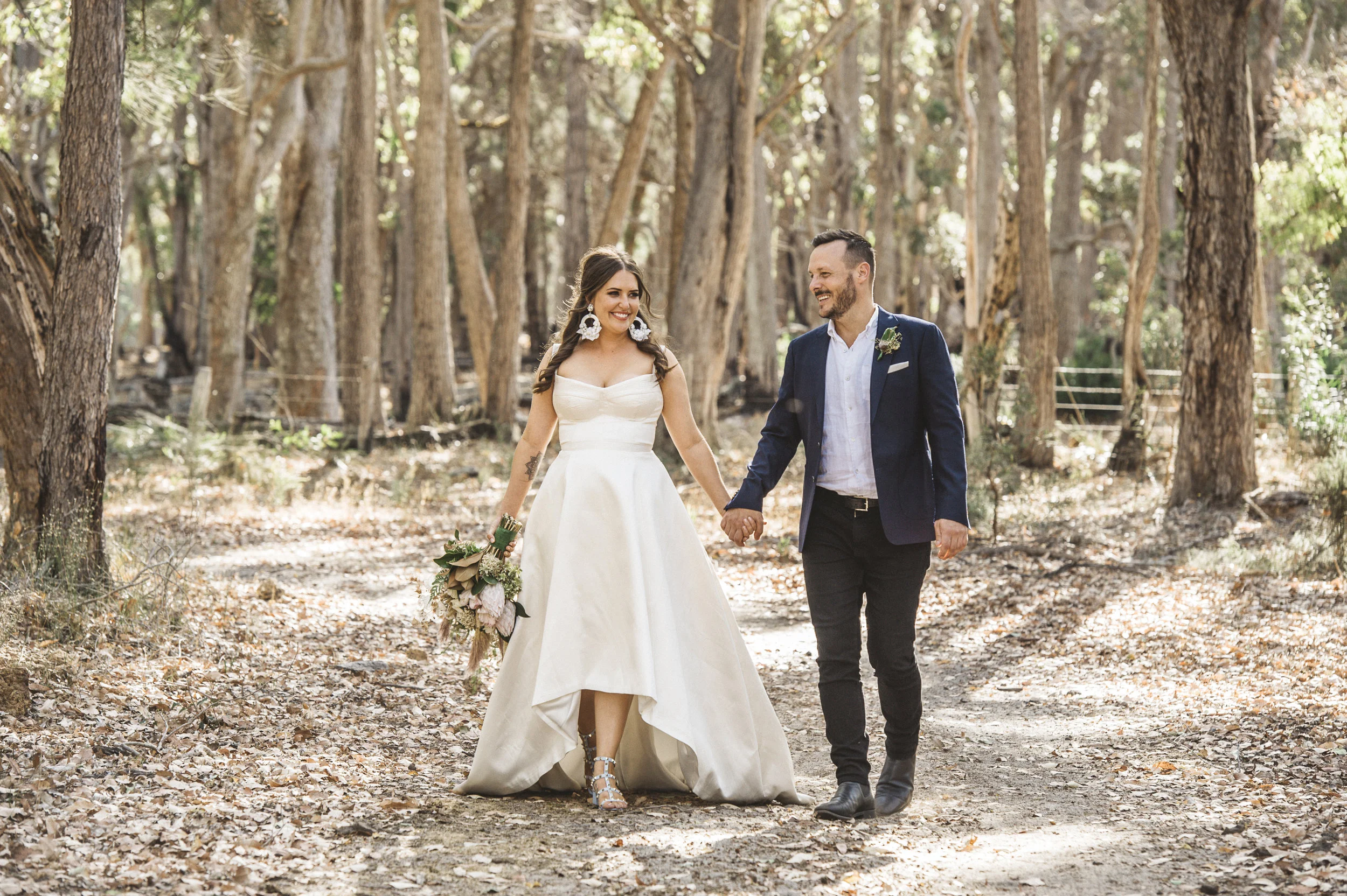 groom and bride holding hands with flower bouquet in the woods beautiful