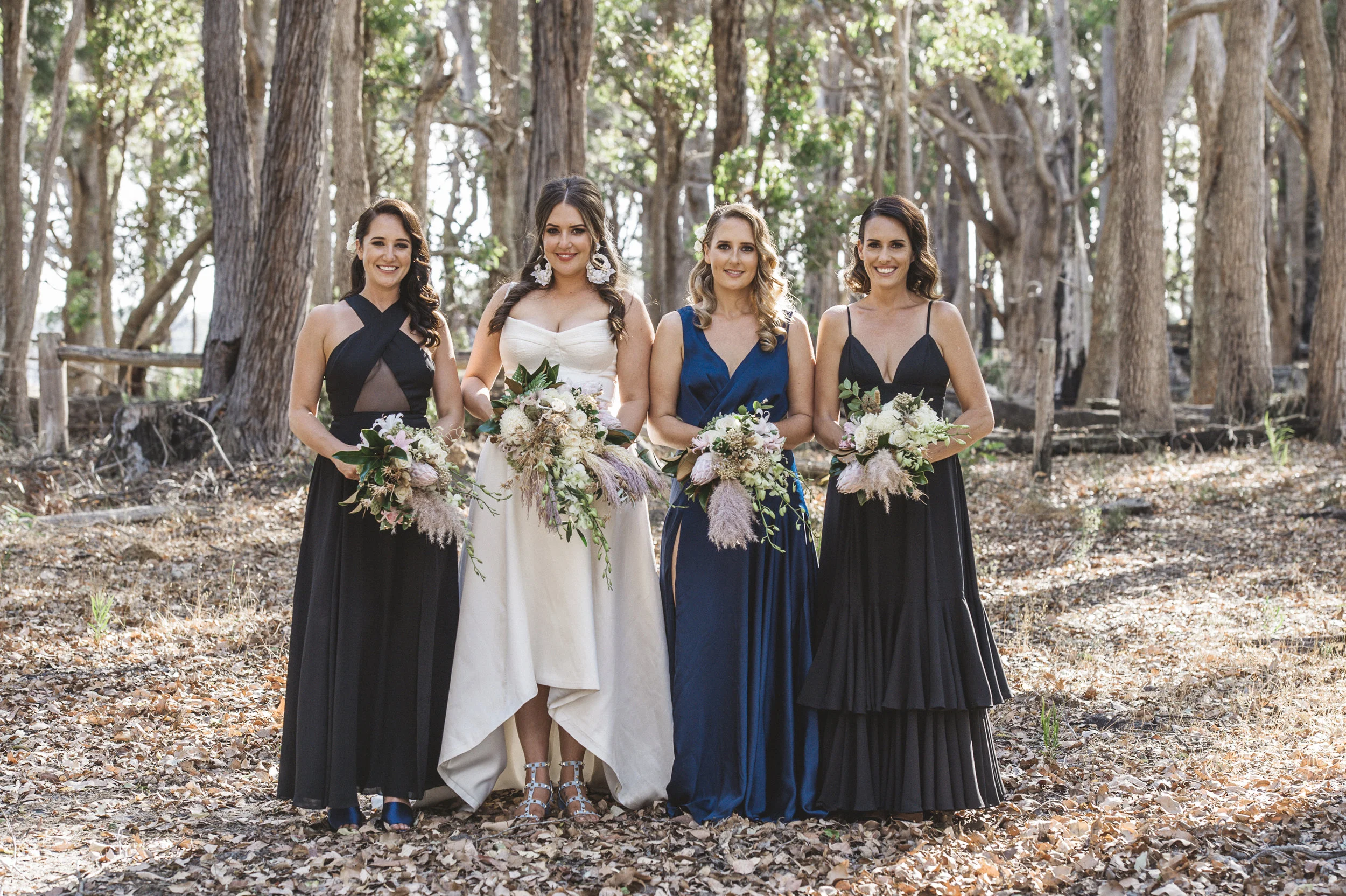 Bride and her brides maids with bouquets posing for photo happy