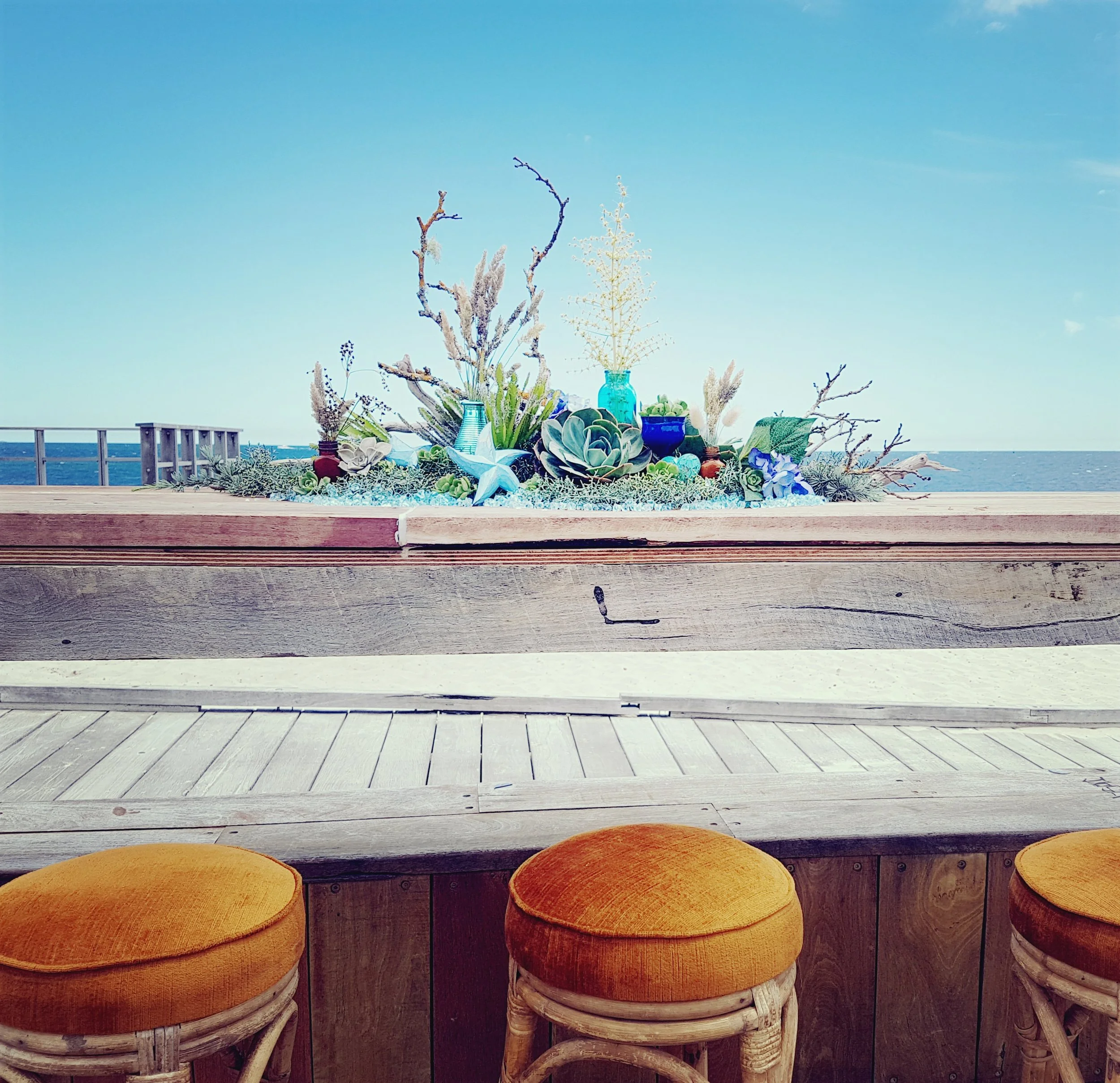 bar stools on the beach with a view and flowers decoration
