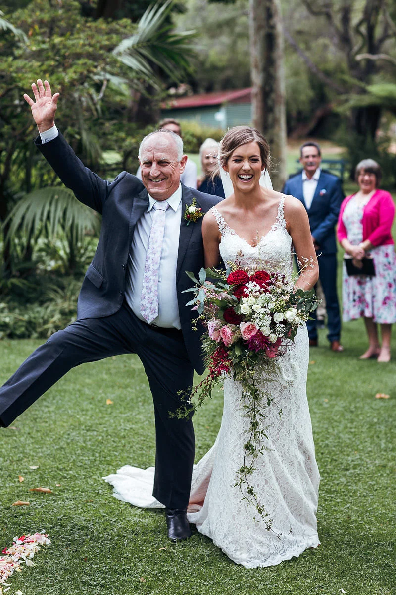 posing for a photo bride with bouquet of flowers guests watching