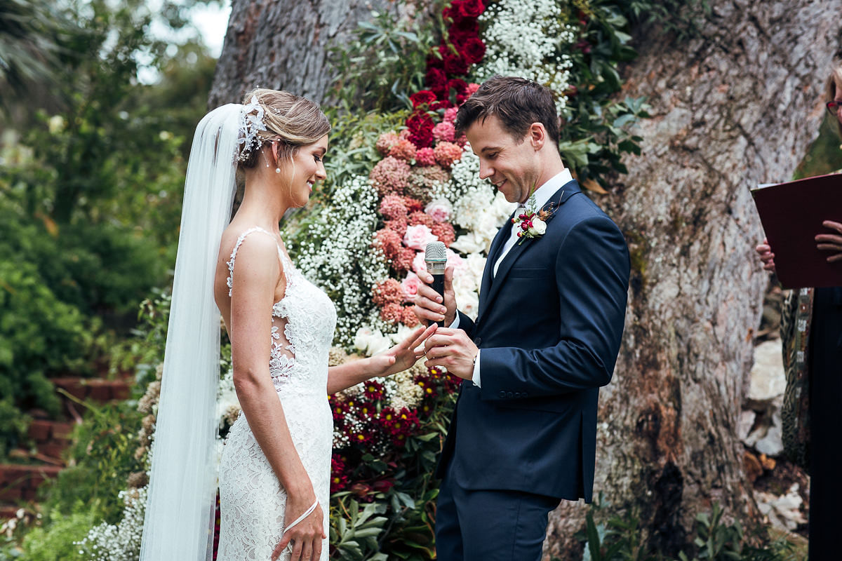 groom putting ring on the bride beautiful wedding tree altar