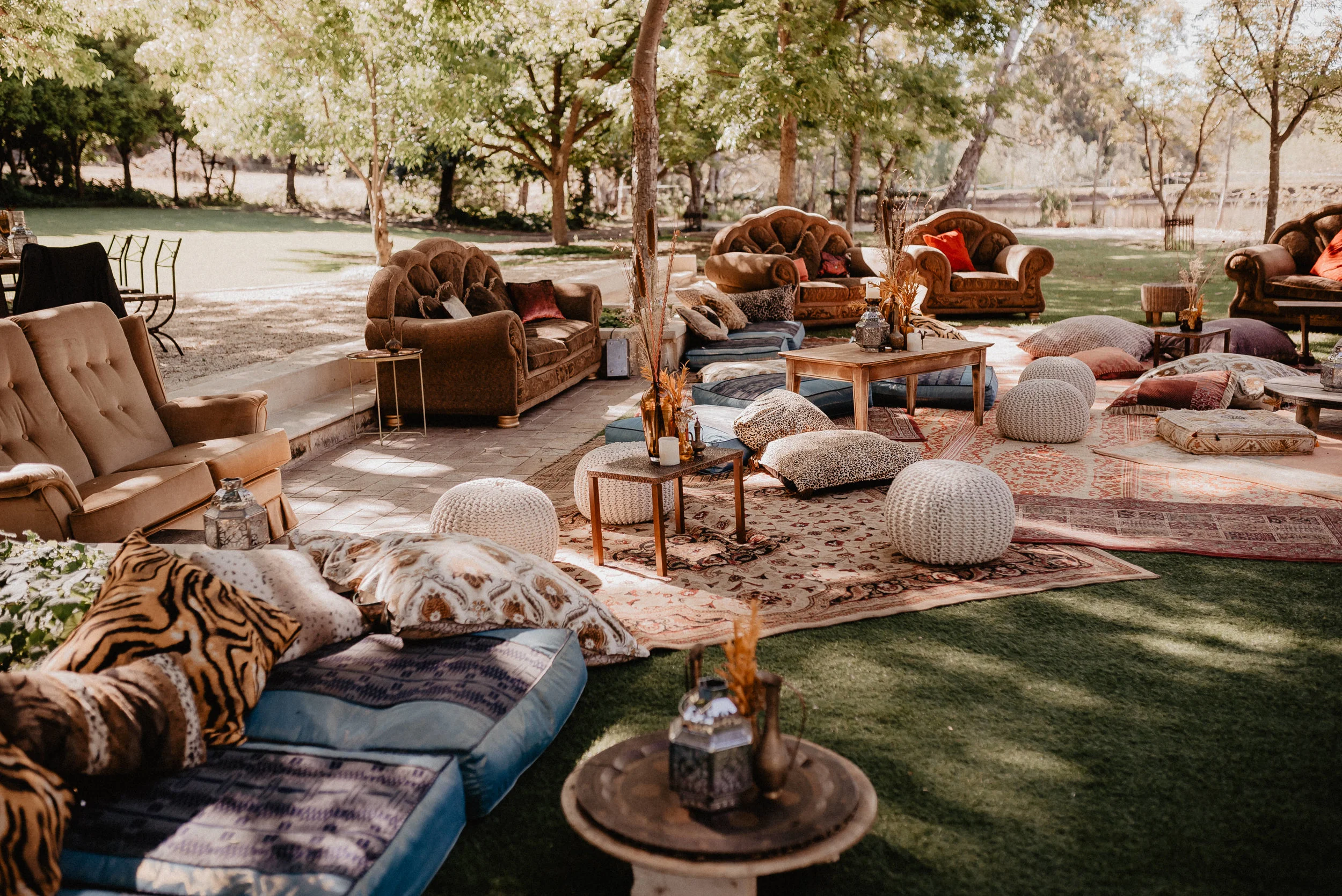 garden wedding setup with couches pillows flowers and a lawn under trees wedding