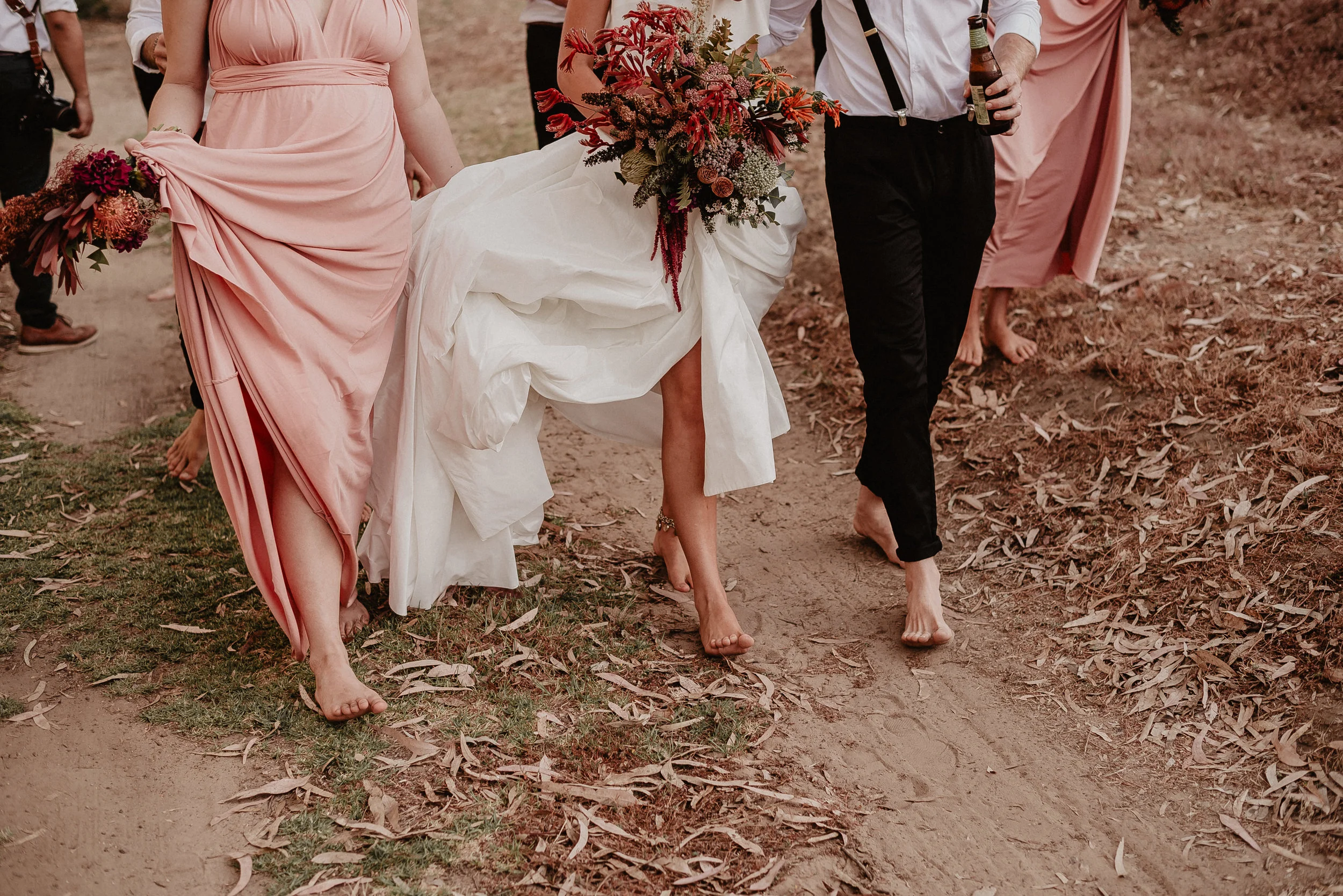 groom and bride with bride maid walking holding gown