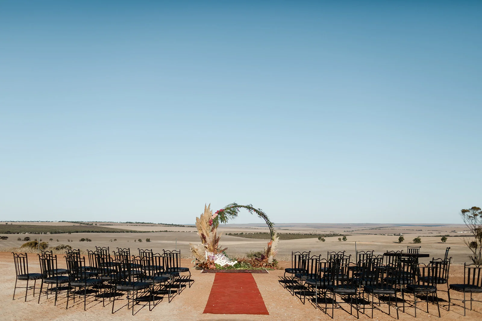 Round arbor with red carpet and black chairs in a desert environment