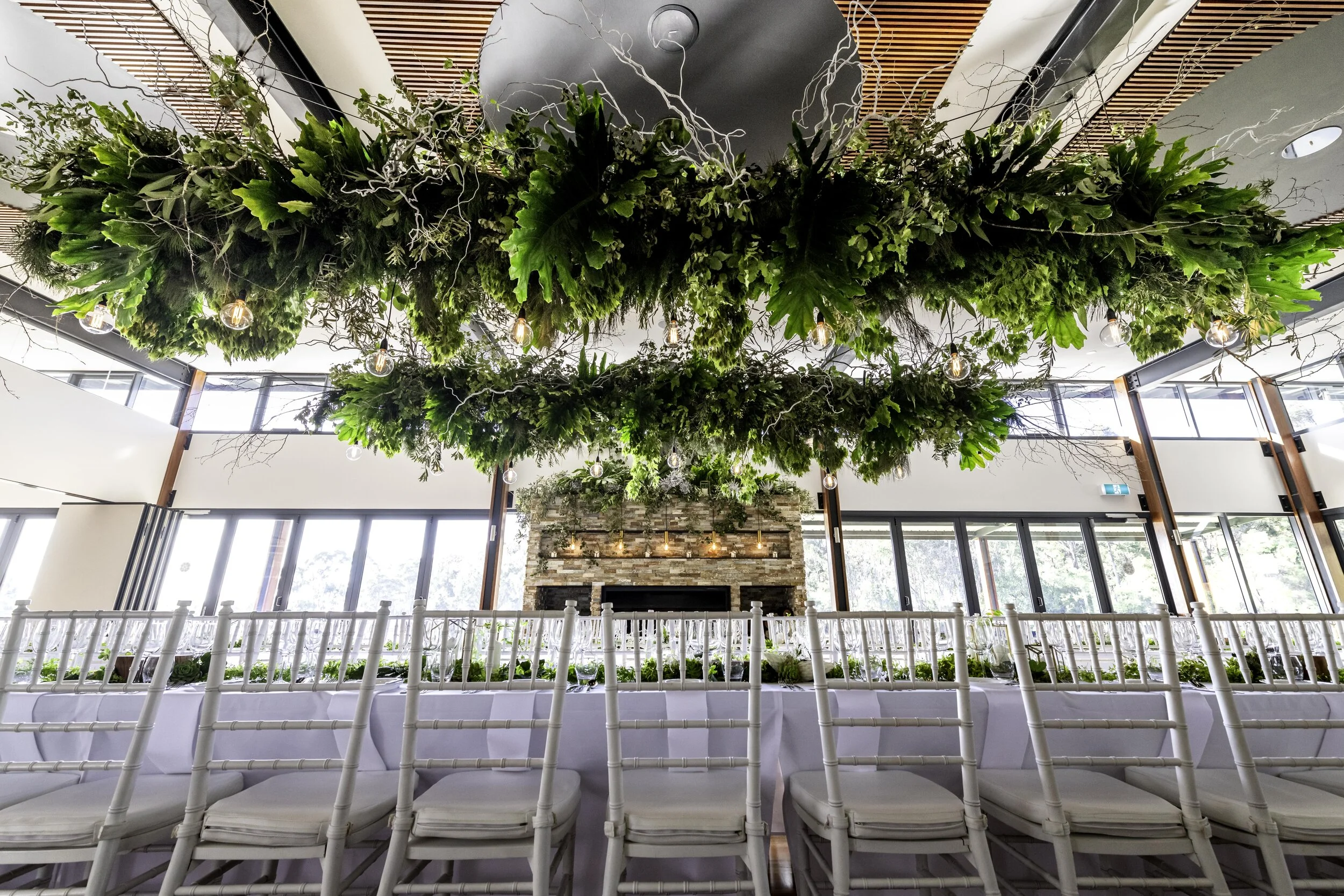 long wedding table with greenery hanging installation