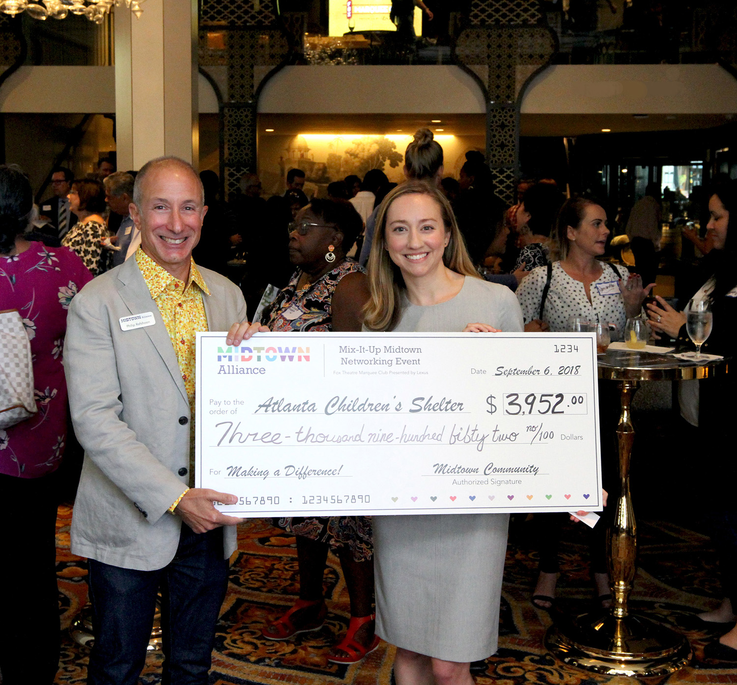 Midtown Alliance Director of Member Engagement Philip Rafshoon presents a check to Sarah Leary of the Atlanta Children’s Shelter at a Mix-It-Up Midtown networking event at the Fox Marquee Club.