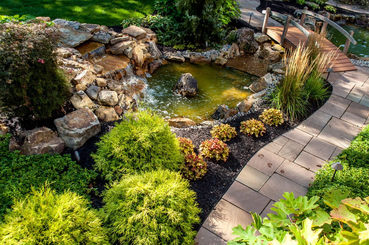 An-overview-of-two-ponds,-a-water-feature-and-lush-plantings-in-a-back-yard-landscape-designed-by-Sundown-Gardens.jpg