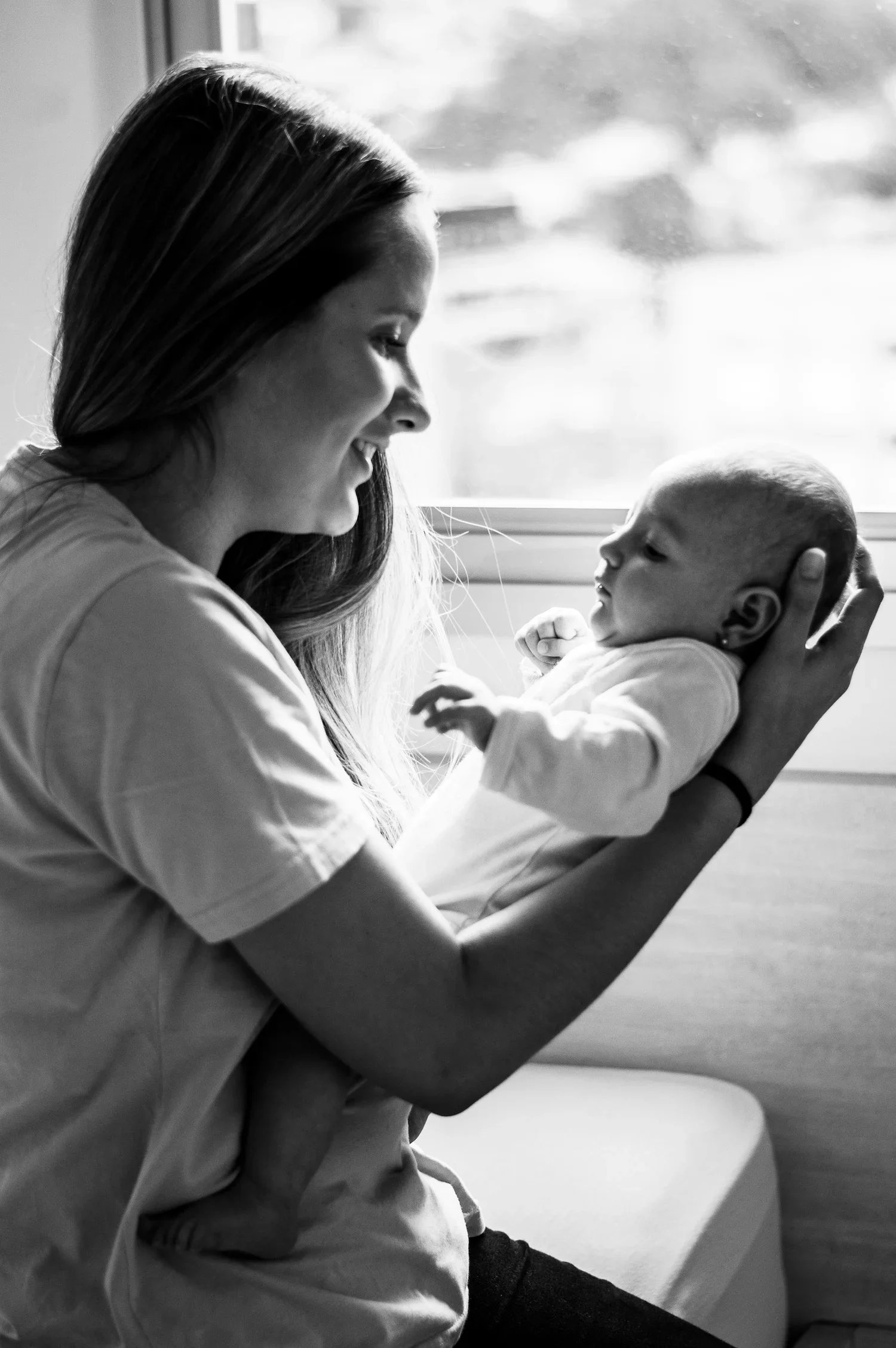 Black and white image of a new mom holding a newborn baby at home.