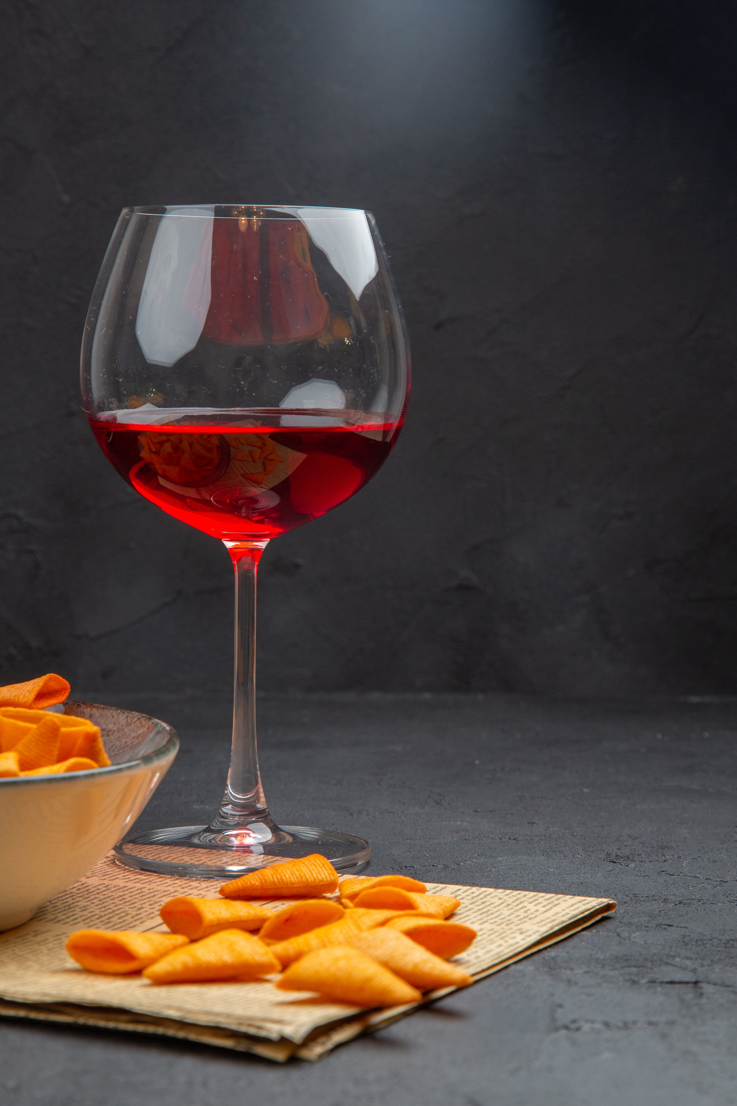 half-shot-delicious-potato-chips-inside-outside-bowl-red-wine-glass-old-newspaper.jpg