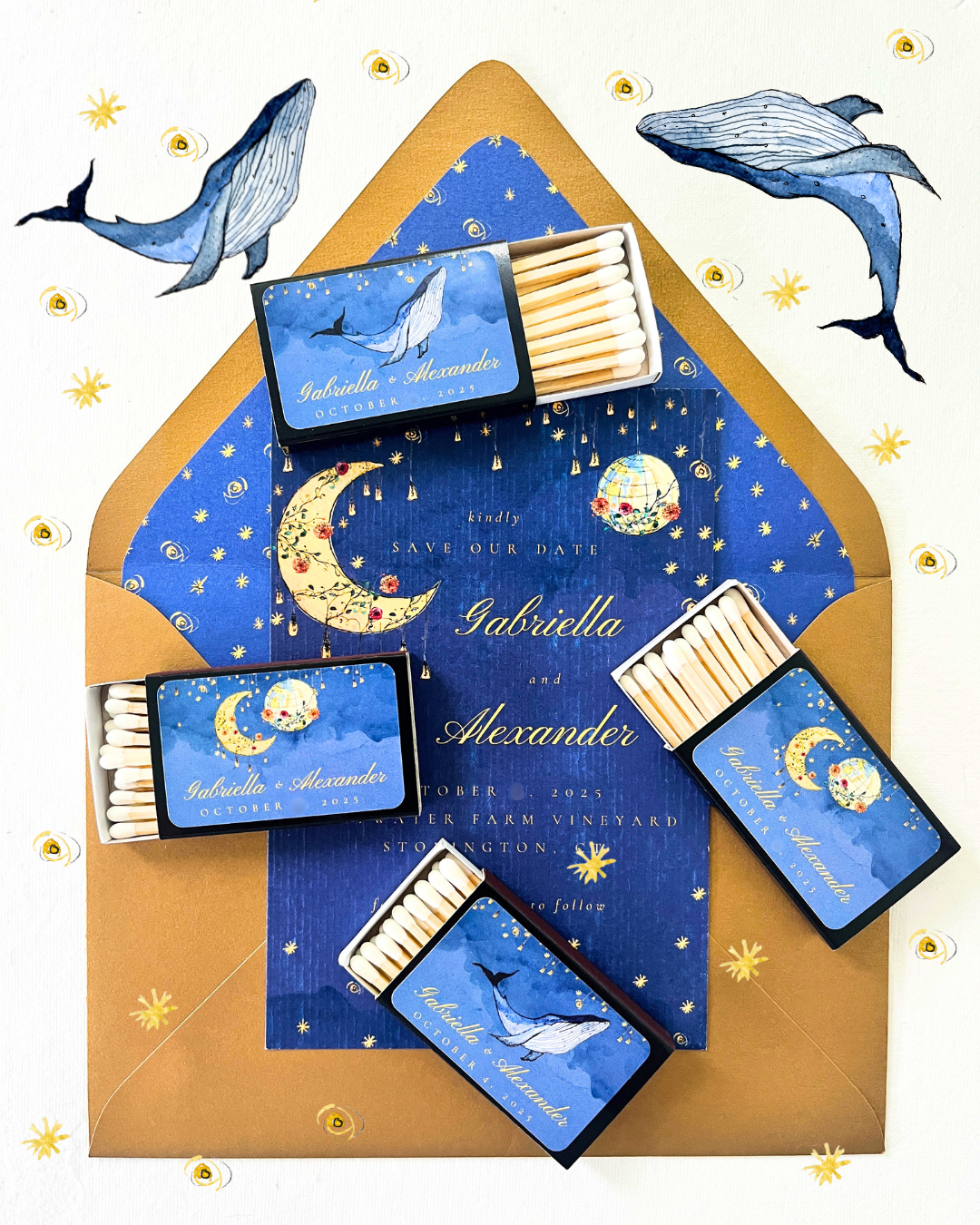 Wedding save-the-date cards and matchboxes with whale and moon designs on a decorated background.