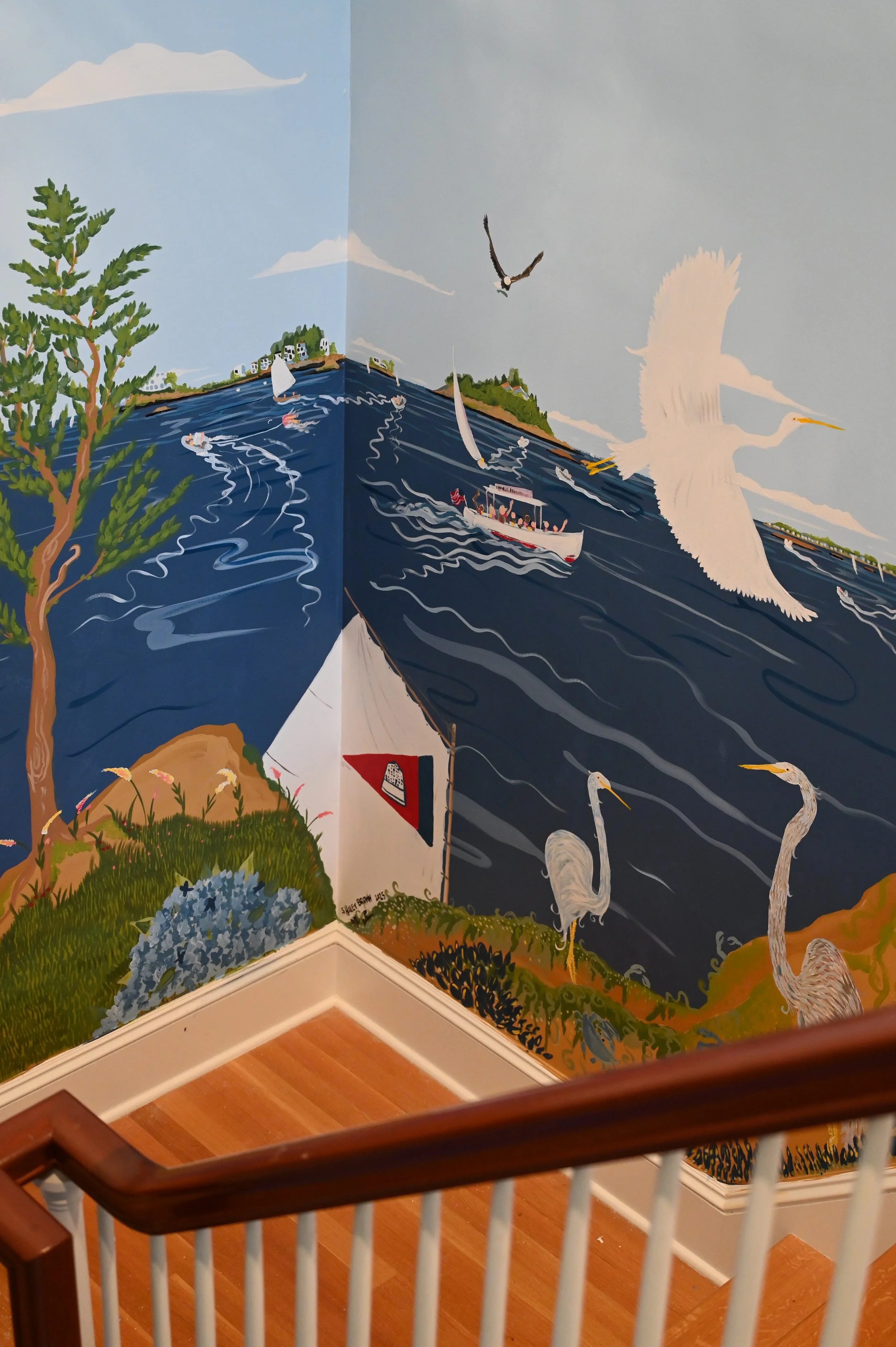 A mural depicting a coastal scene with boats, seagulls, herons, and a tree, painted on the corner walls of a staircase landing.