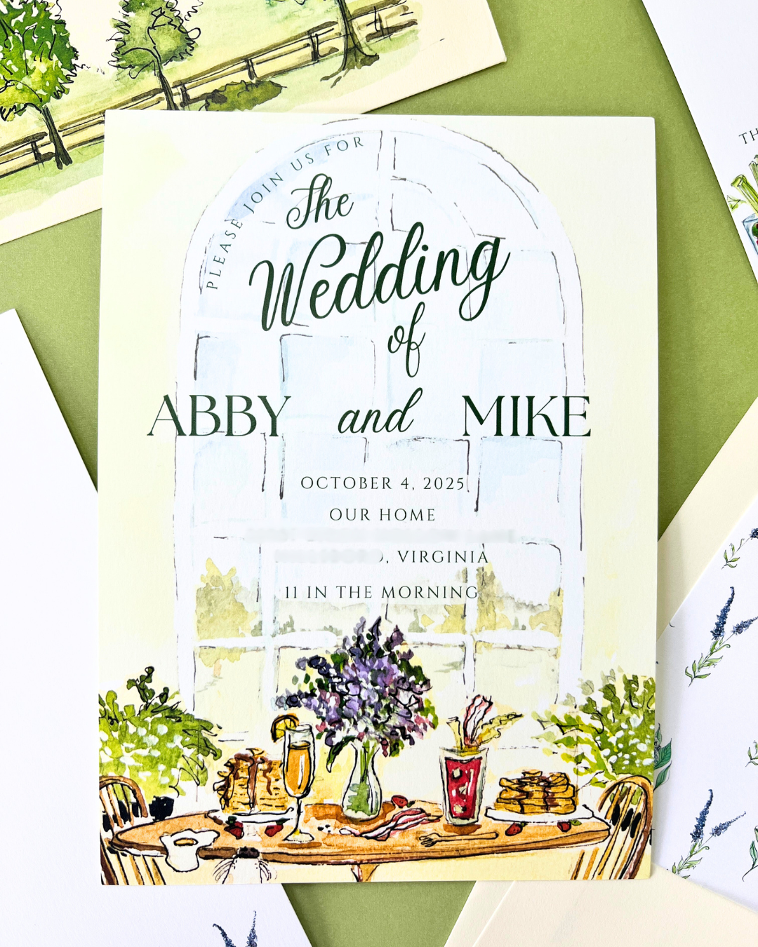 Wedding invitation featuring a watercolor illustration of a dining table with a vase of purple flowers, two drinks, and food, set against a large window.