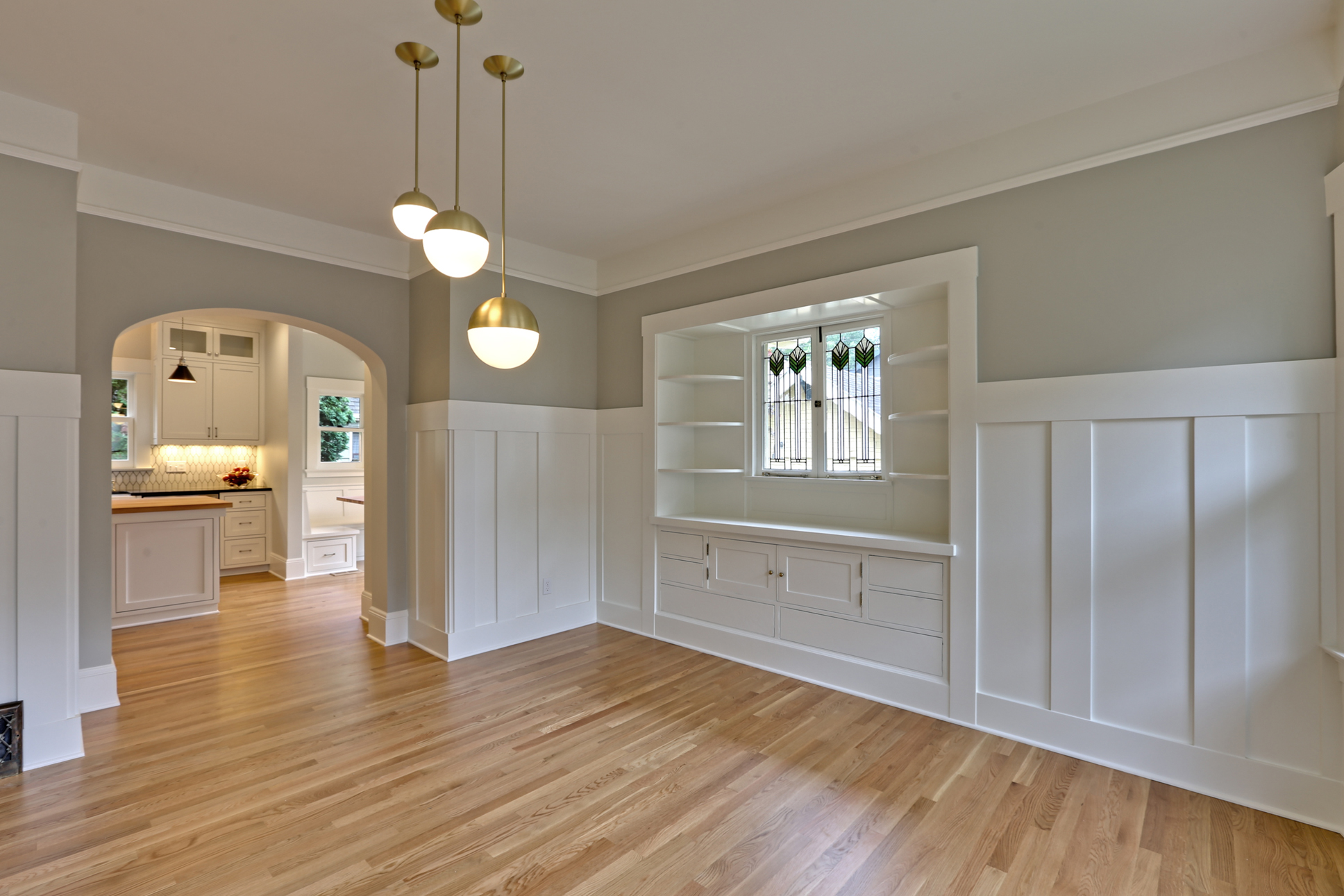  We redesigned the passageway from the dining room into the kitchen for better flow and to match the arches found elsewhere in the home. Fun light fixtures from Rejuvenation compliment the revitalized original cabinets and wainscoting; blending old a