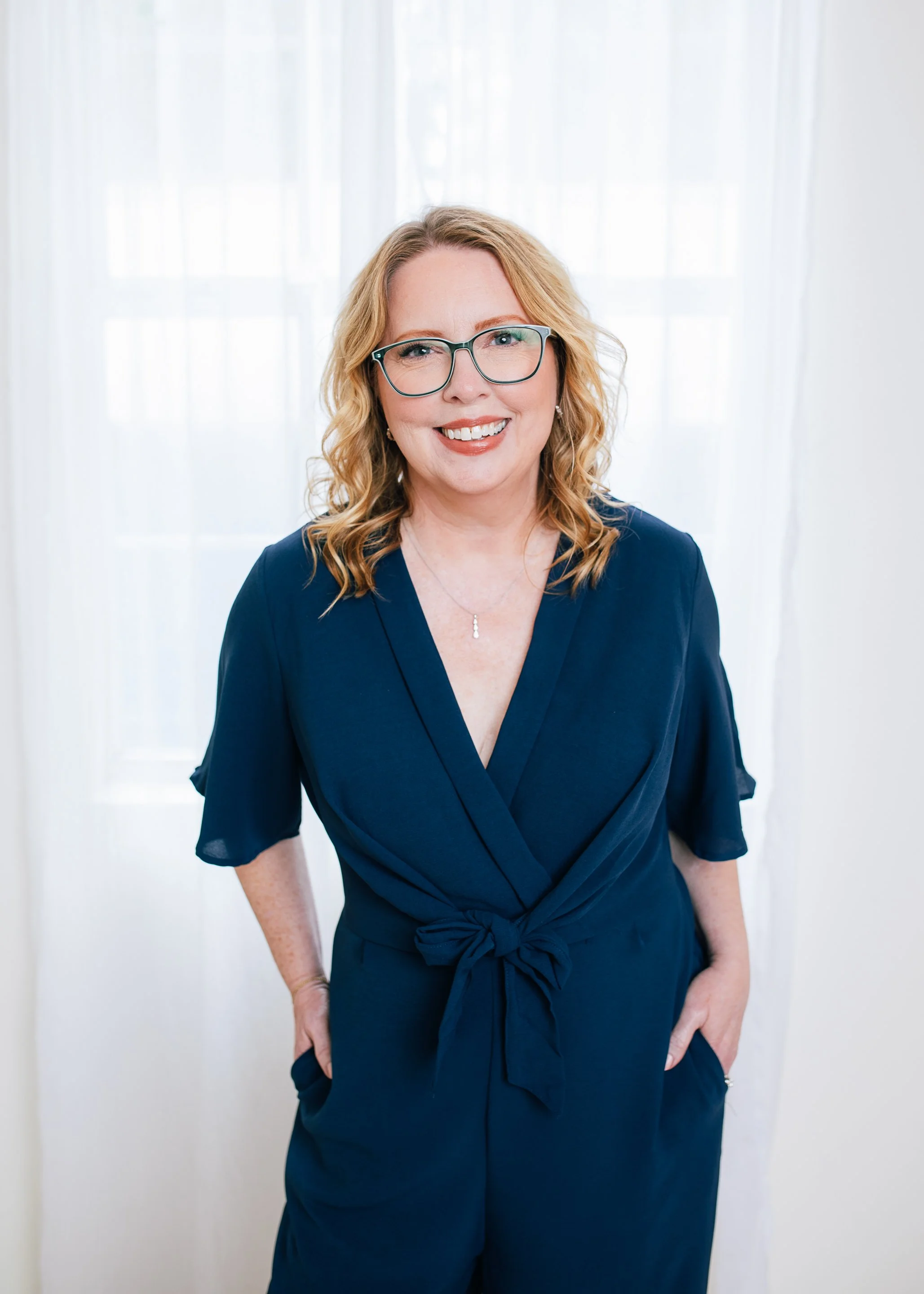 Woman with red/blonde hair poses in a navy jumpsuit for Amanda Faucett Photography's 50 Over 50 photo project in Houston, TX