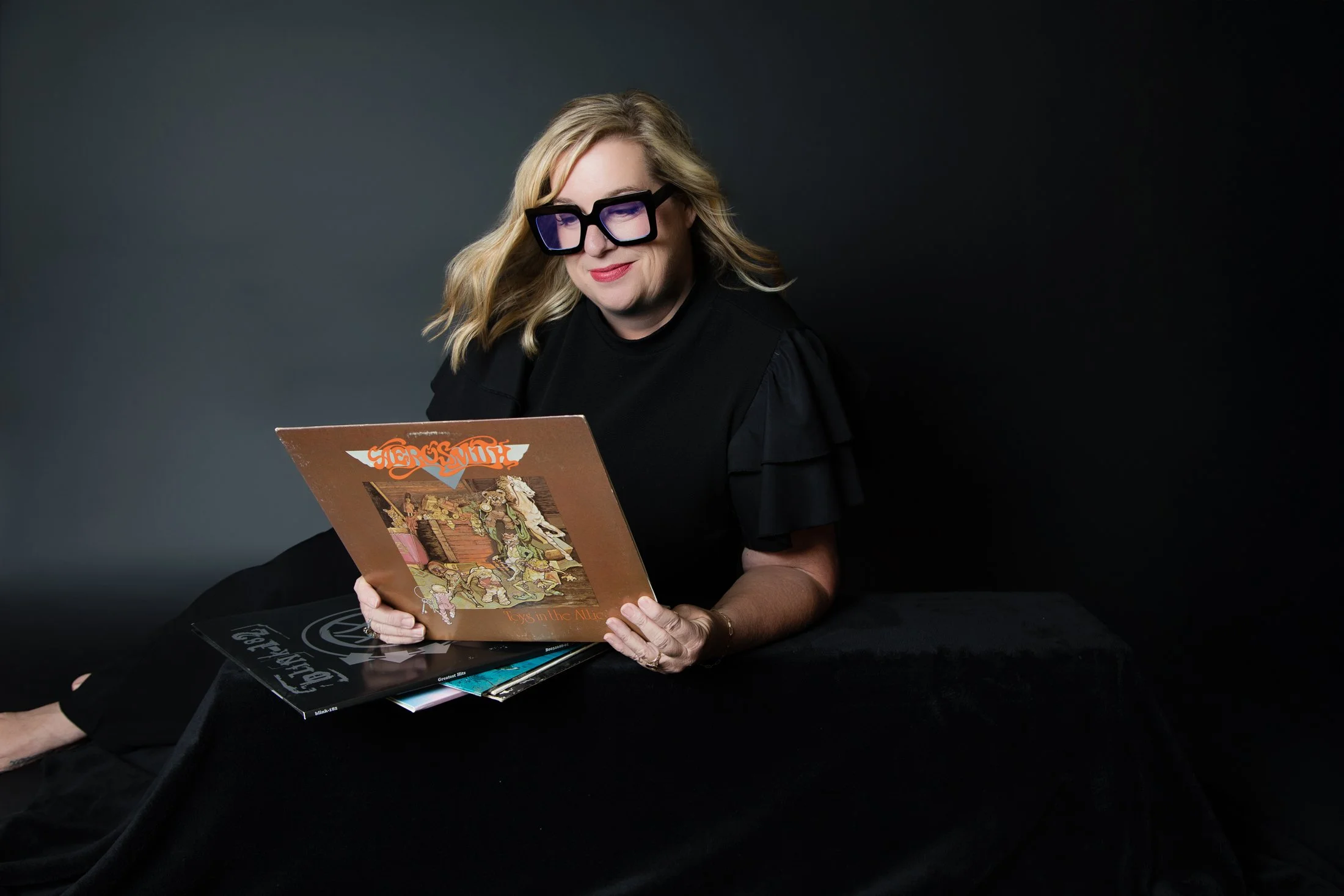 A relaxed portrait of Kim with her vinyl collection in Amanda Faucett's studio for the 50 Over 50 Portrait Experience.