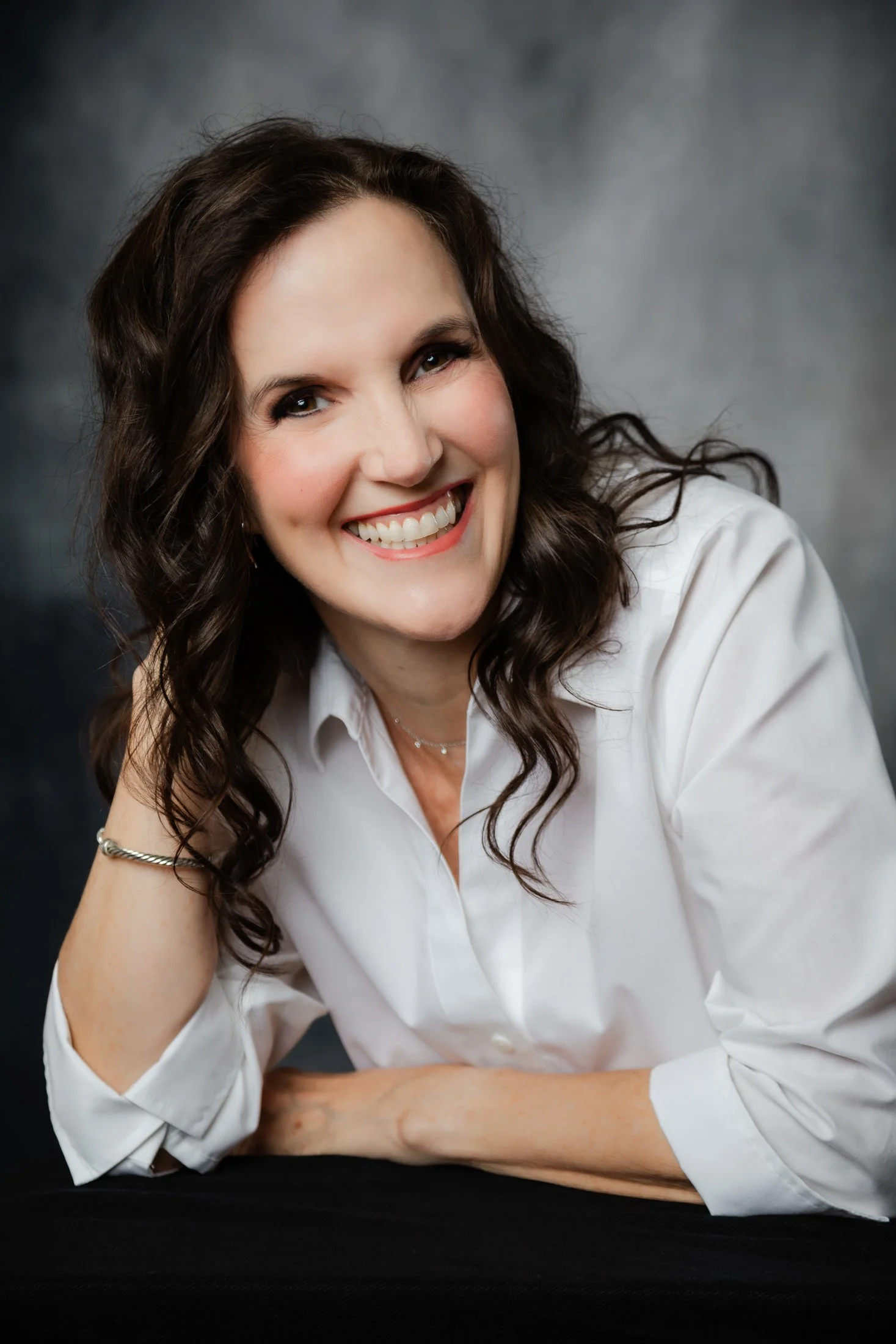 Timeless studio portrait of Laura in a white button-down blouse, celebrating beauty and confidence after 50.