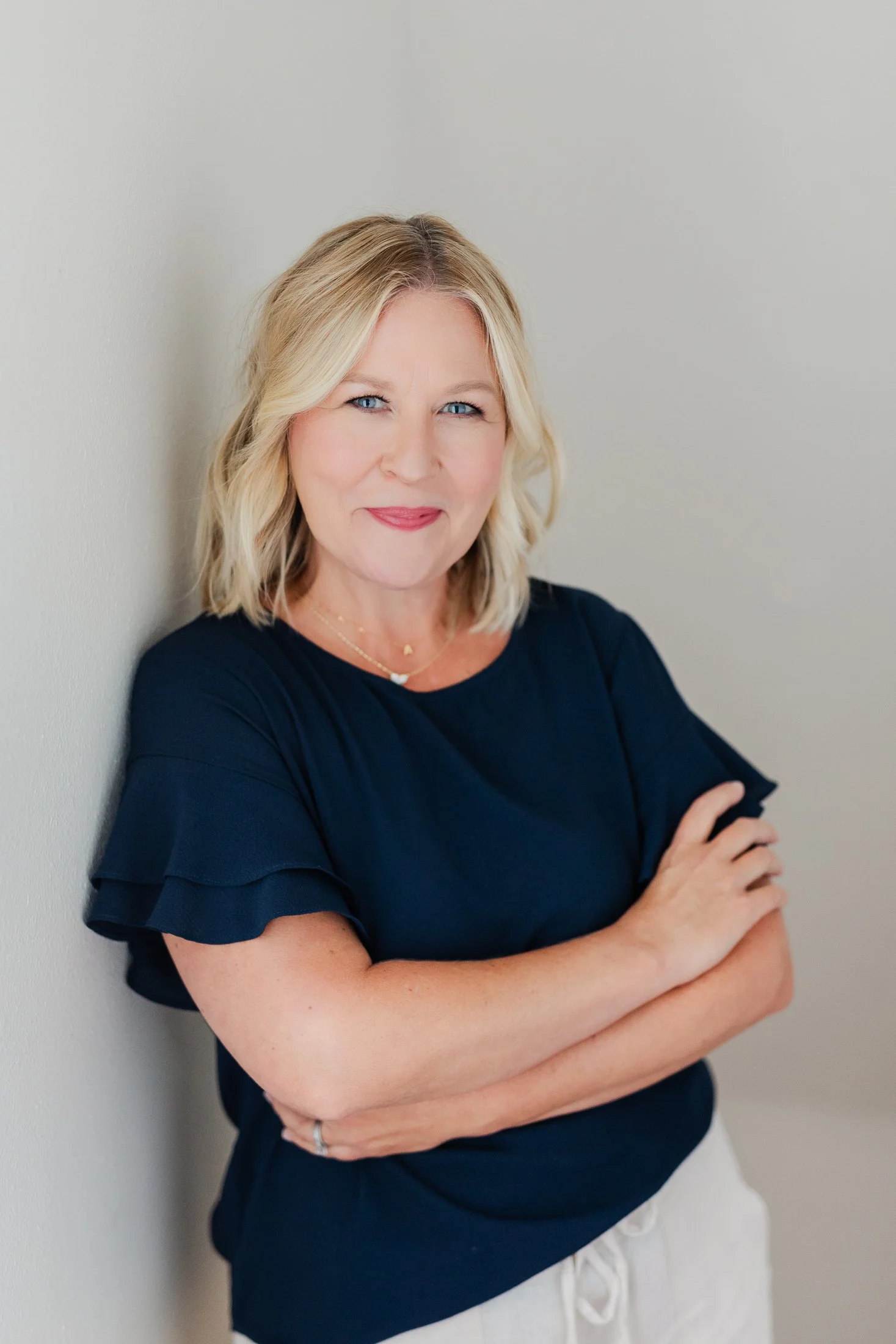 Elegant author portrait of Ann wearing a navy blouse and leaning against a wall, from the Wise Women 50 Over 50 Portrait Experience in Houston by Amanda Faucett.