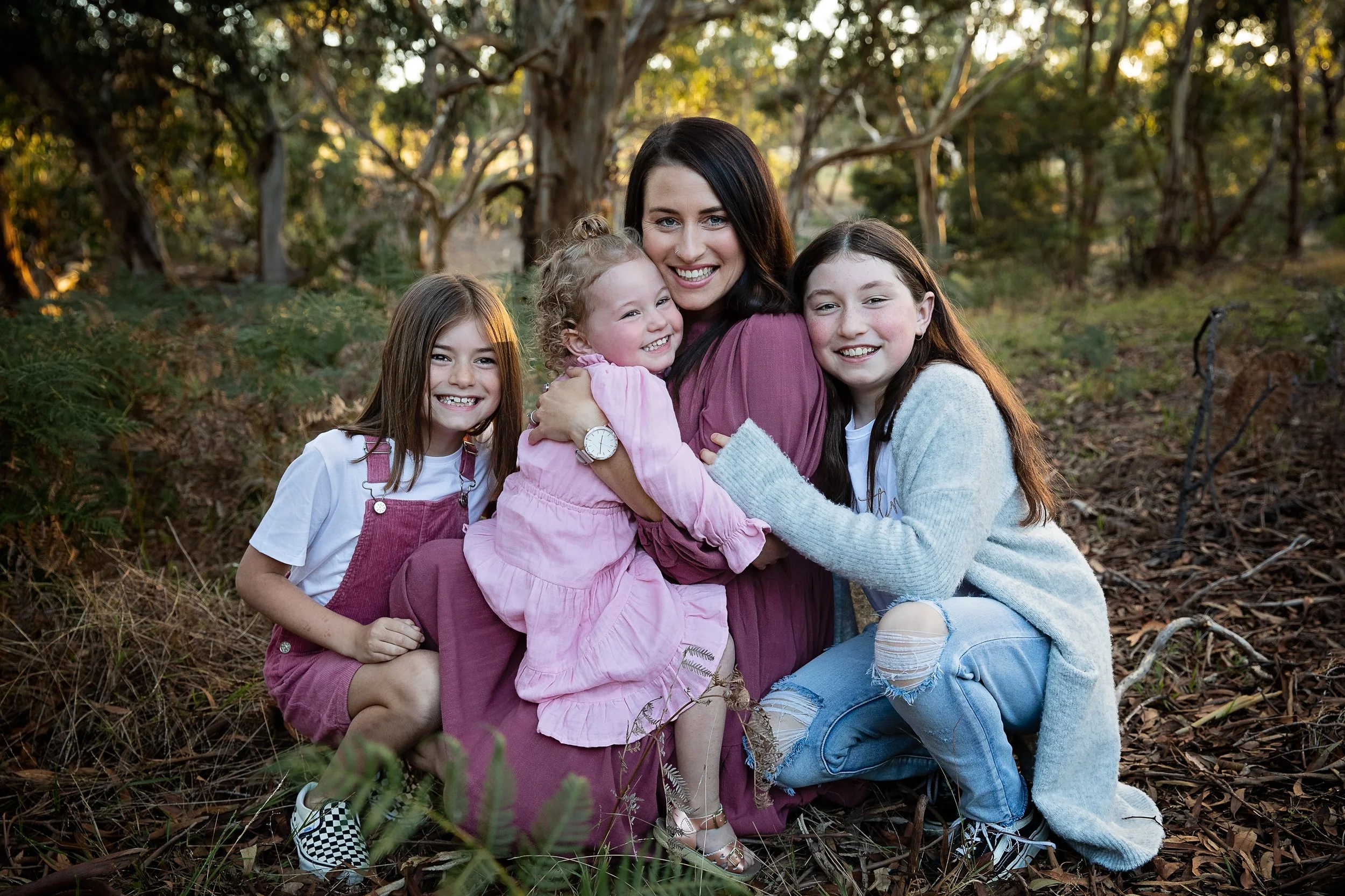 Mum and her three daughters cuddling together in the bush