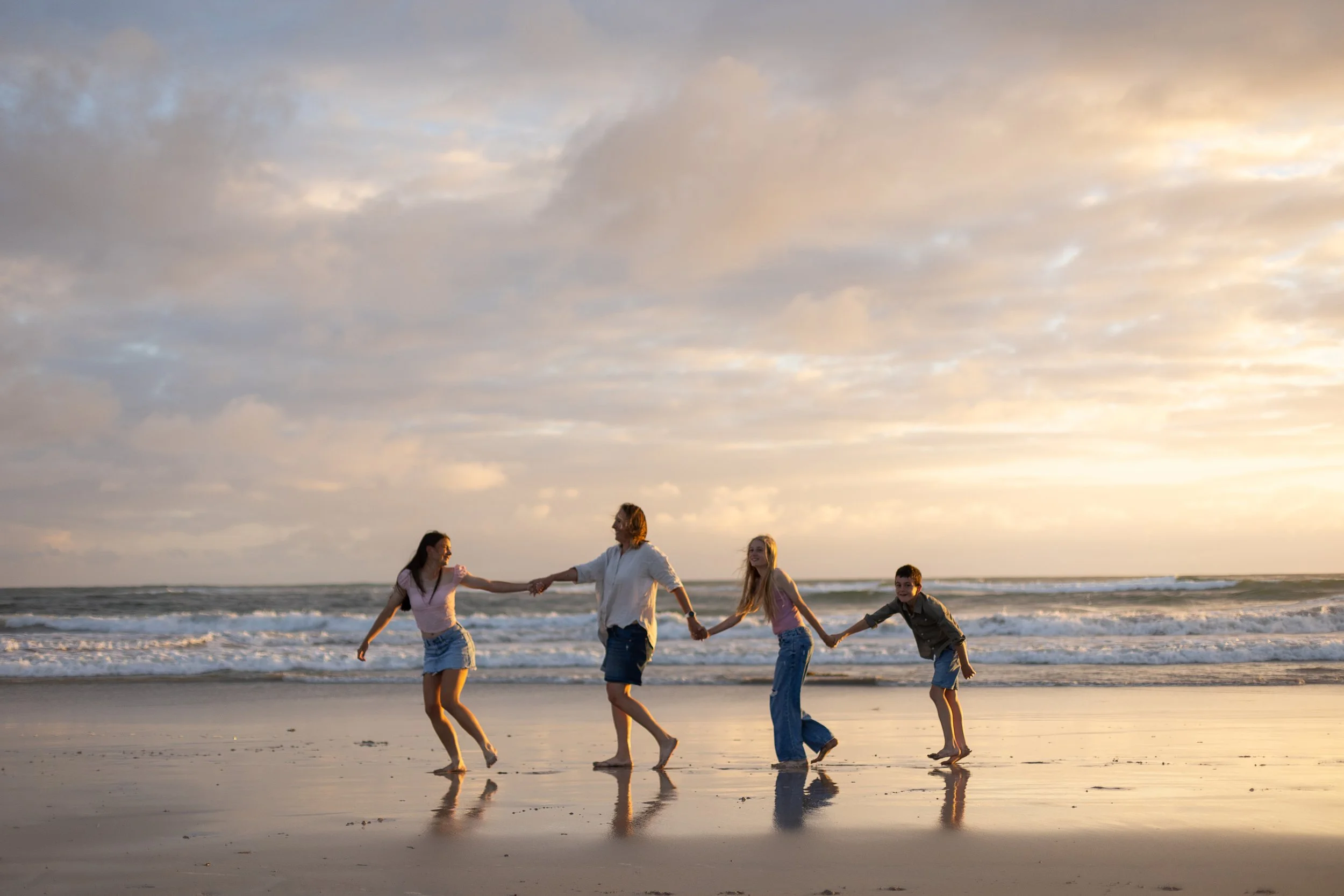 Family walking together on a Torquay beach at sunset
