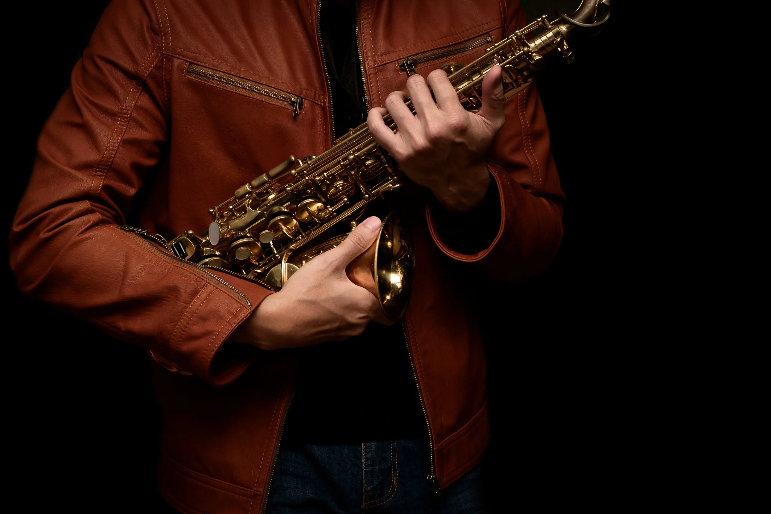 musician saxophone player holding his saxophone on isolated black background.