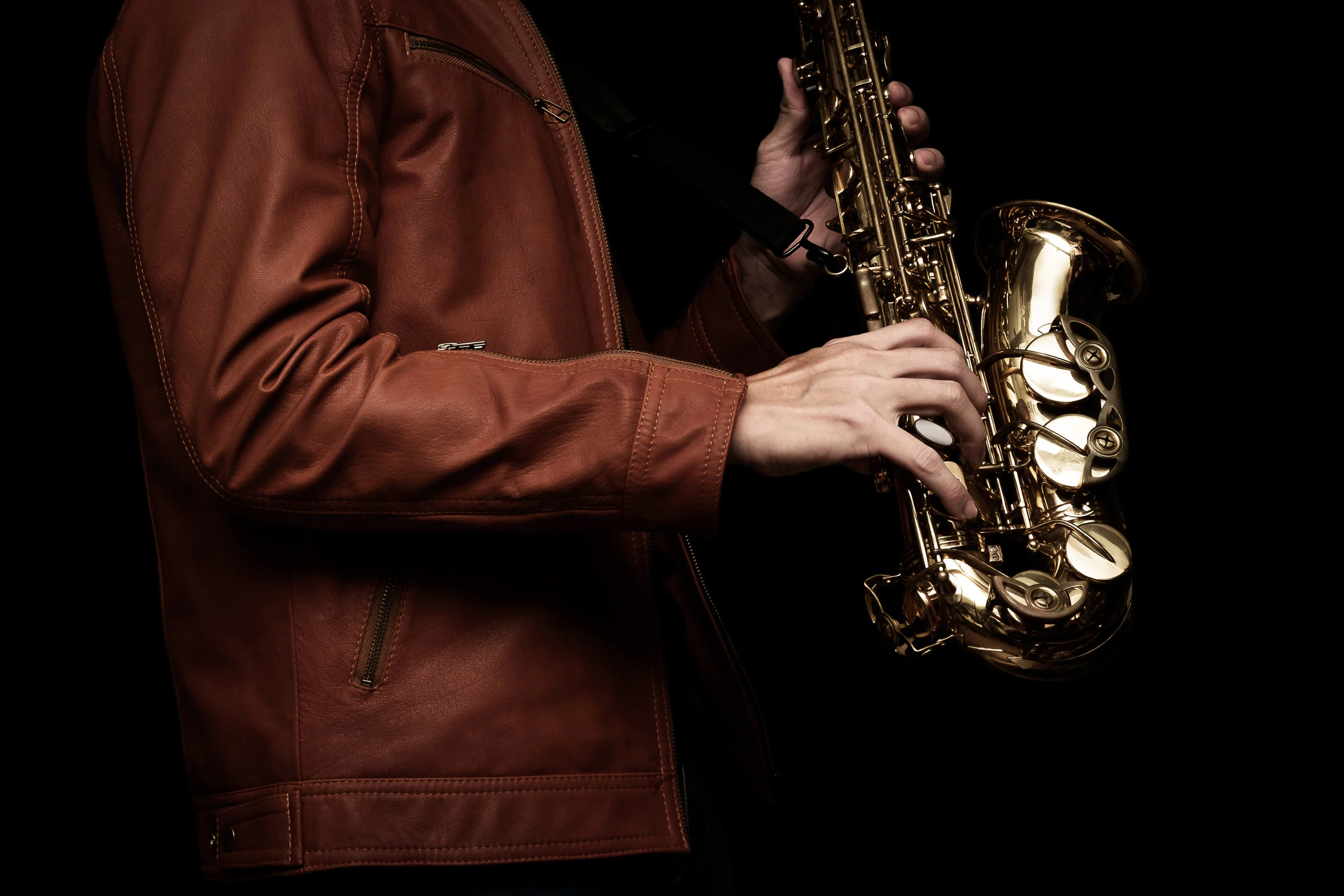 Jazz saxophone musician in the leather jacket, closeup.