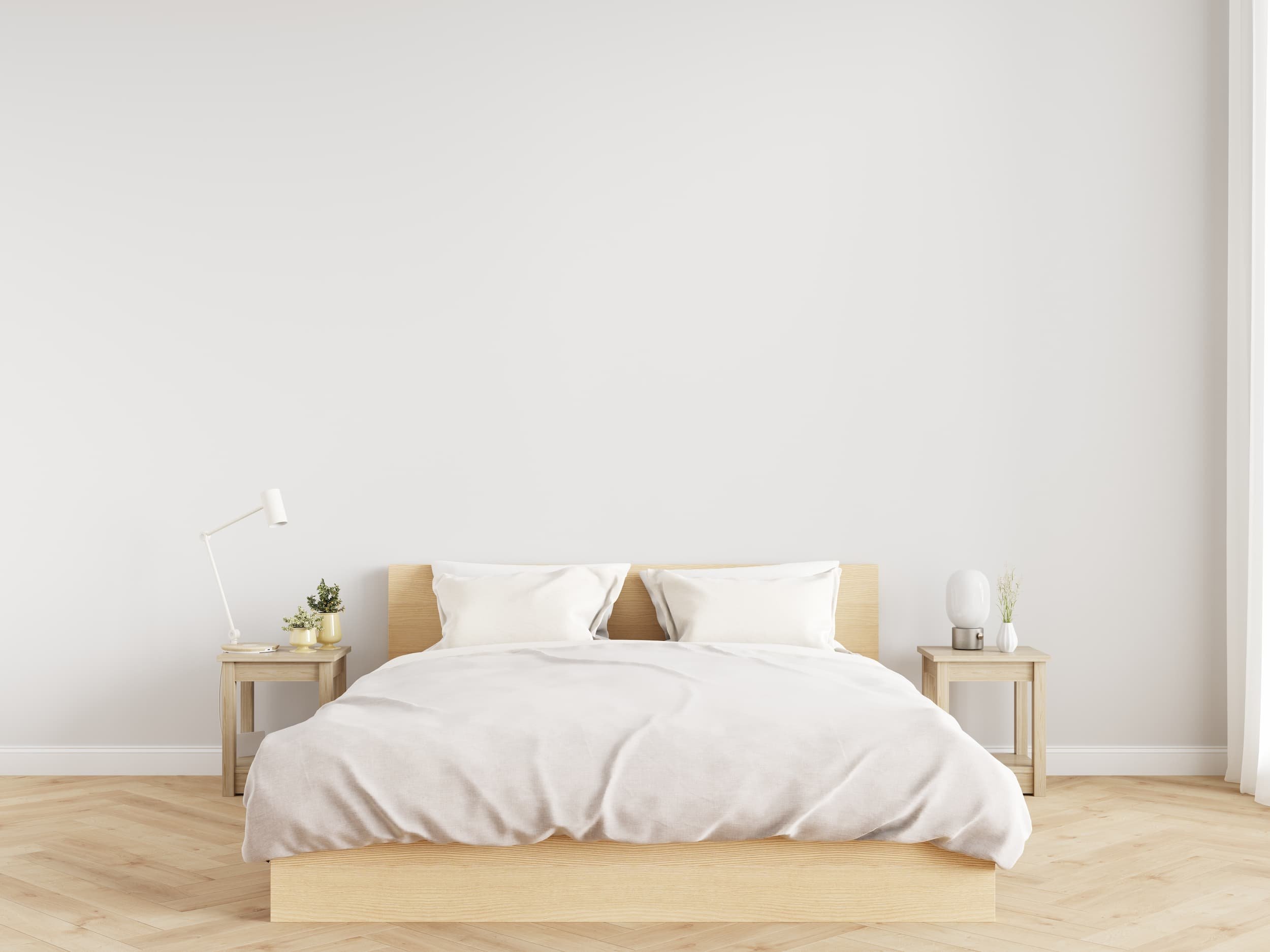 A simple bedroom with two nightstands and lots of unused space on the wall behind the bed.