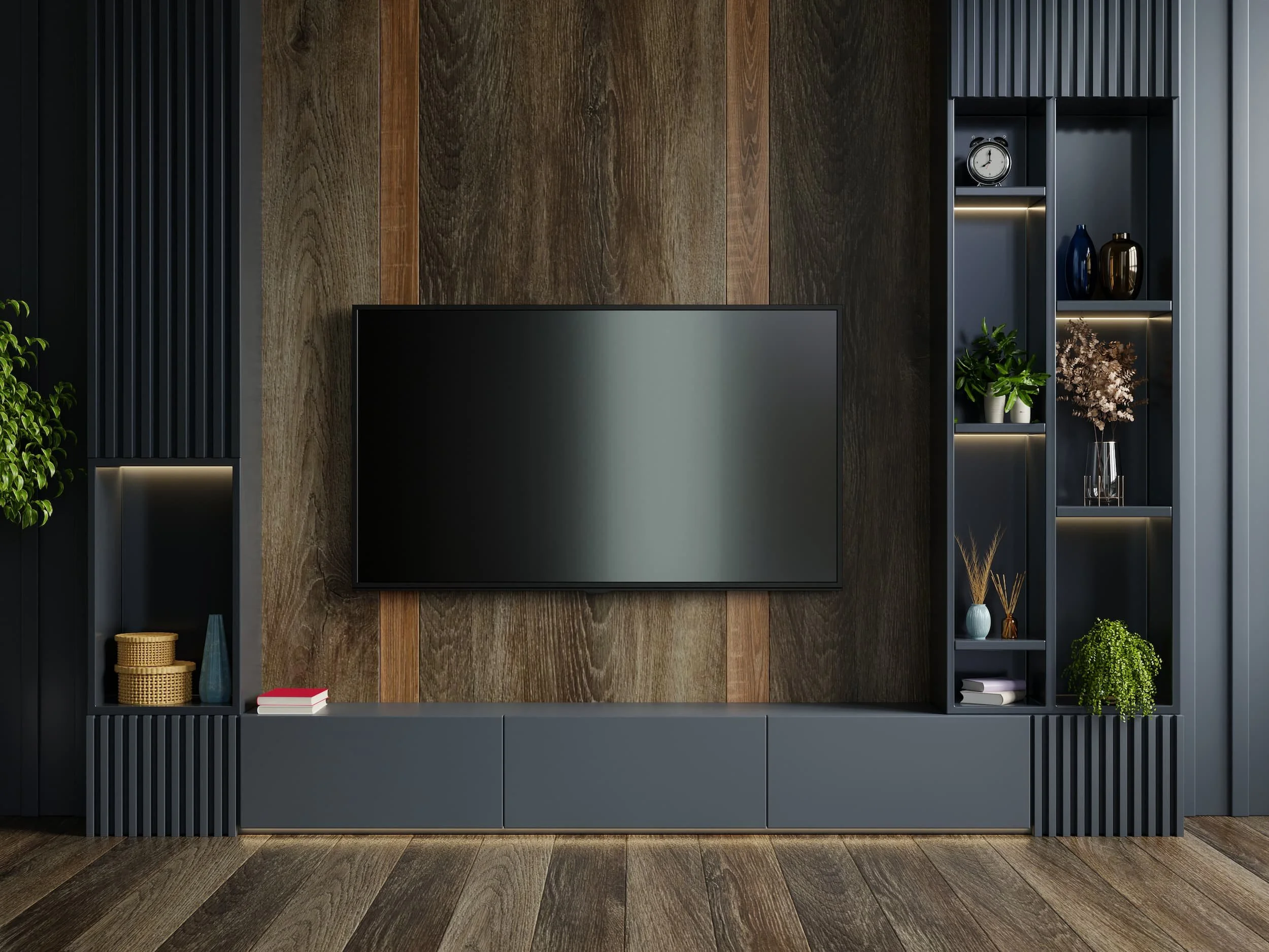 A sleek, modern media wall, featuring a large TV against wooden cladding with built-in black shelves and drawers surrounding it.