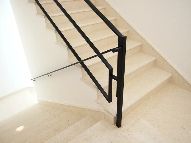 Close-up detail of the matt black steel finish and the clean joinery of the handrail construction.