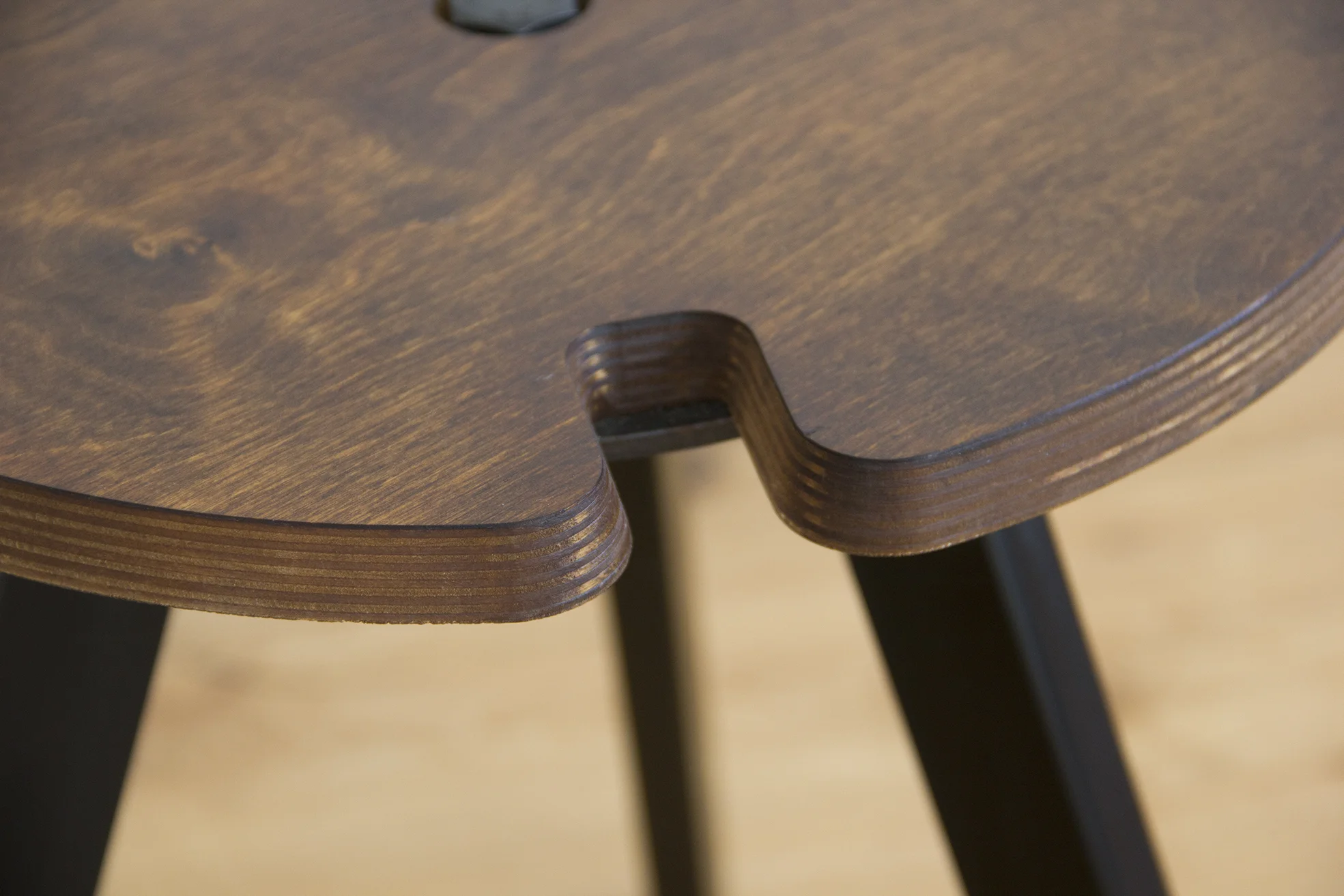 Underside view revealing the round metal plate that sits slightly wider than the wooden rebates, designed to support the stacked legs and protect the wood finish.