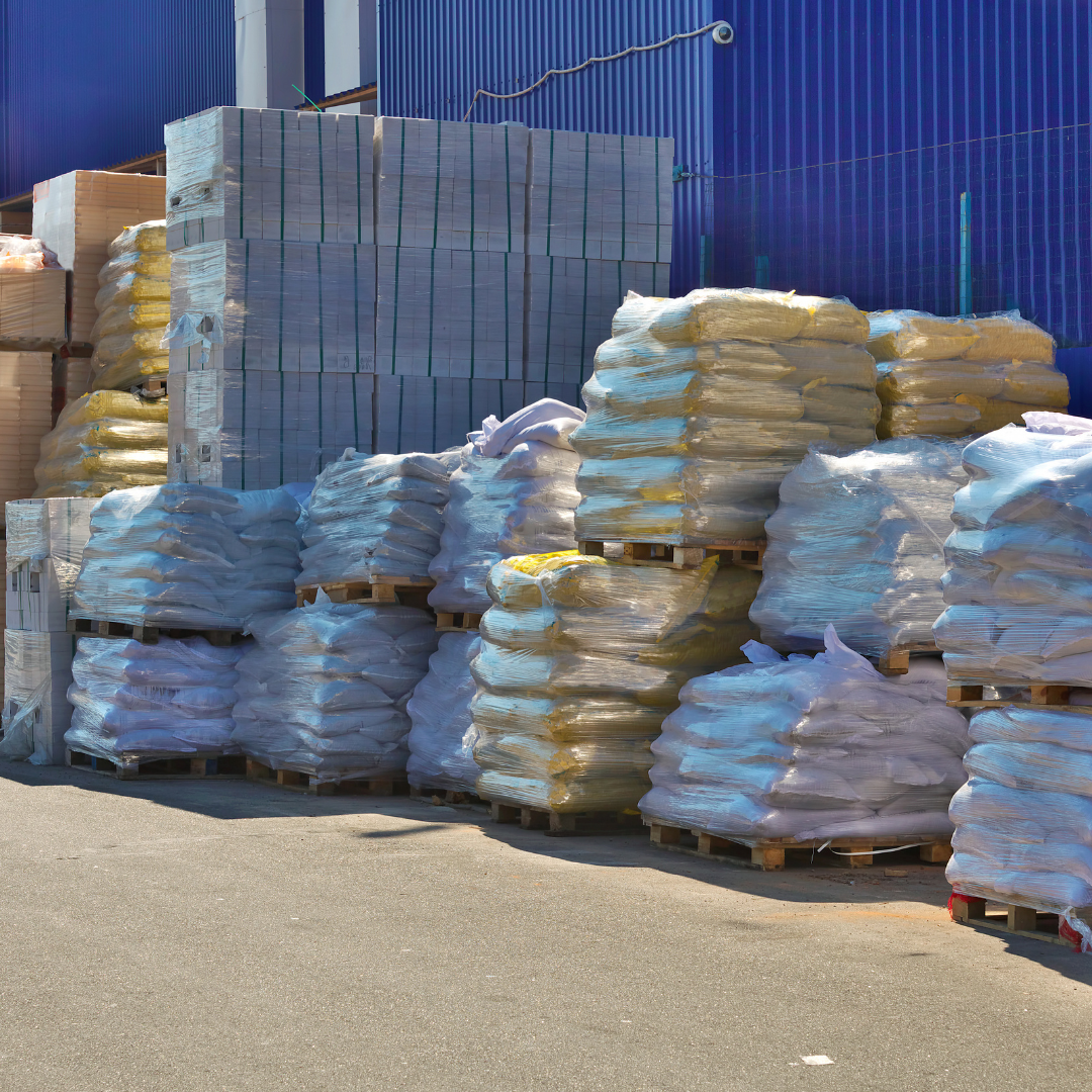 There are several pallets wrapped in plastic that contain construction and building products inside of them.