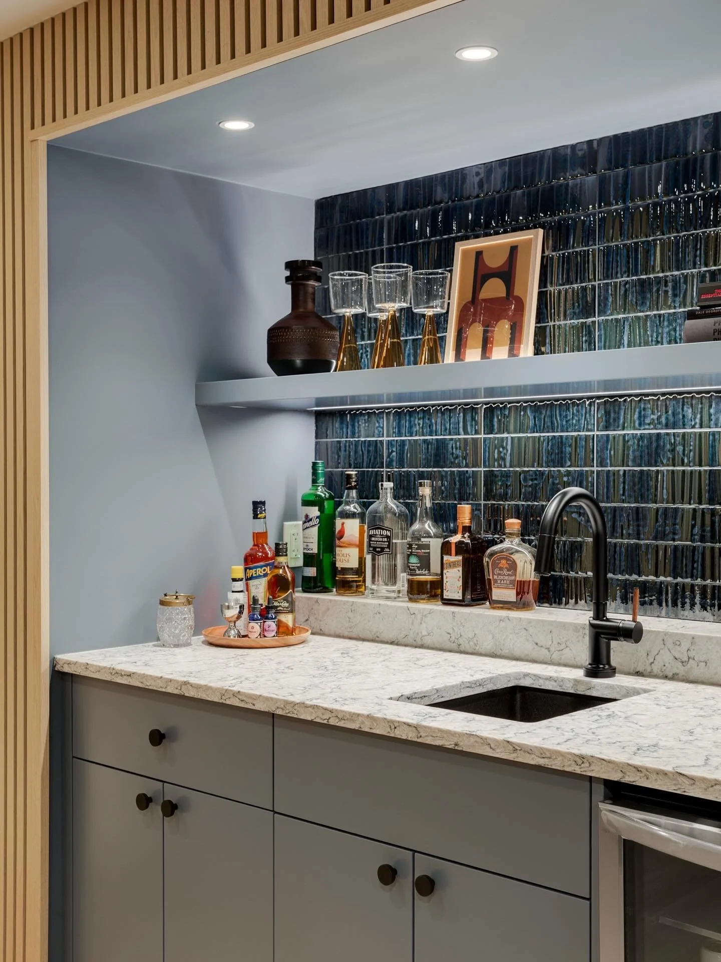 A small wet bar can have just as much &ldquo;wow&rdquo; as a big one! The basement bar at our #SFCoachHillReno project was painted moody blue to match the rest of the basement and given a statement countertop, highly textured backsplash, and wood sla