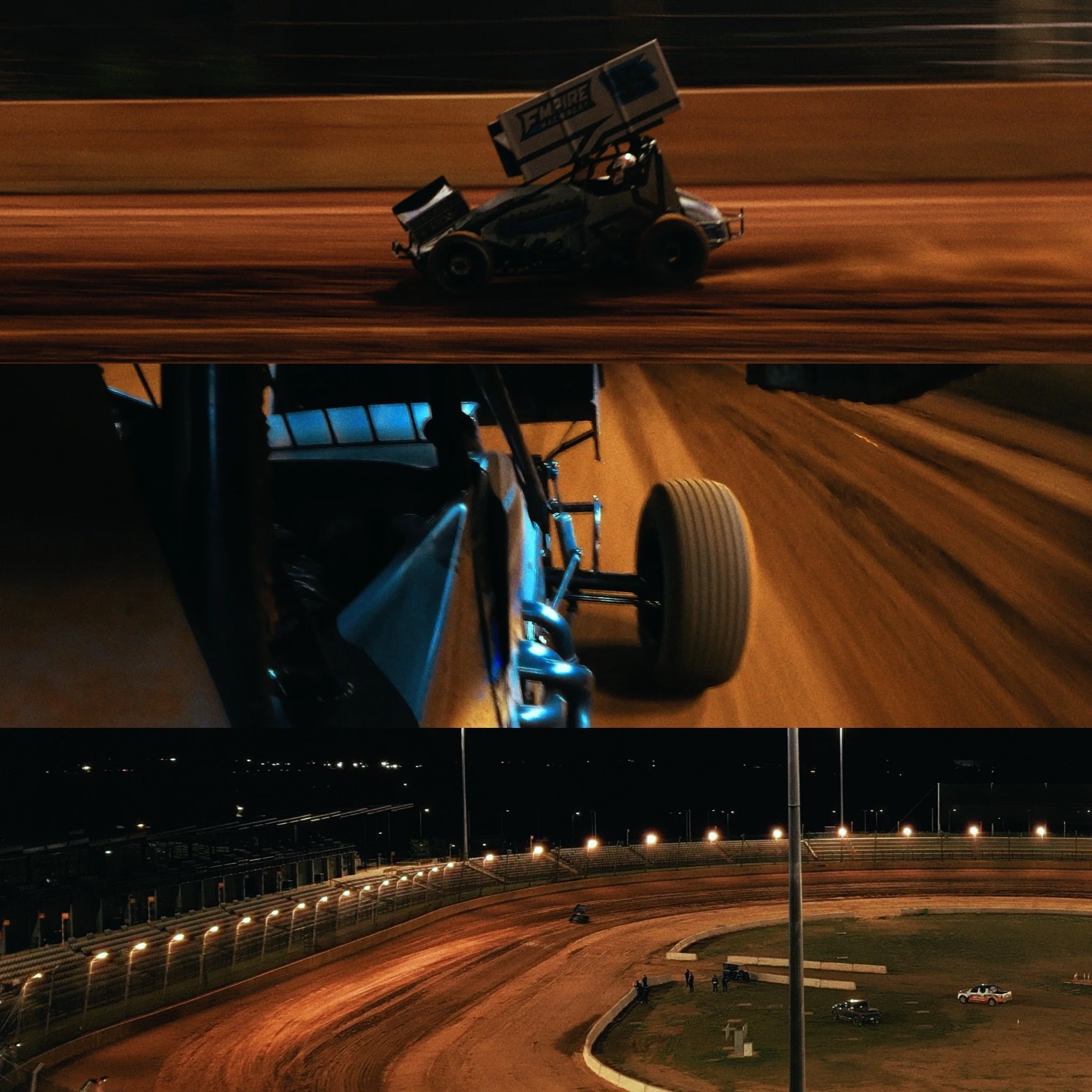 Nighttime view of a dirt race track with a black and white sprint car equipped with a large wing on top racing along the track. In the background, there are empty grandstands and several floodlights illuminating the area.