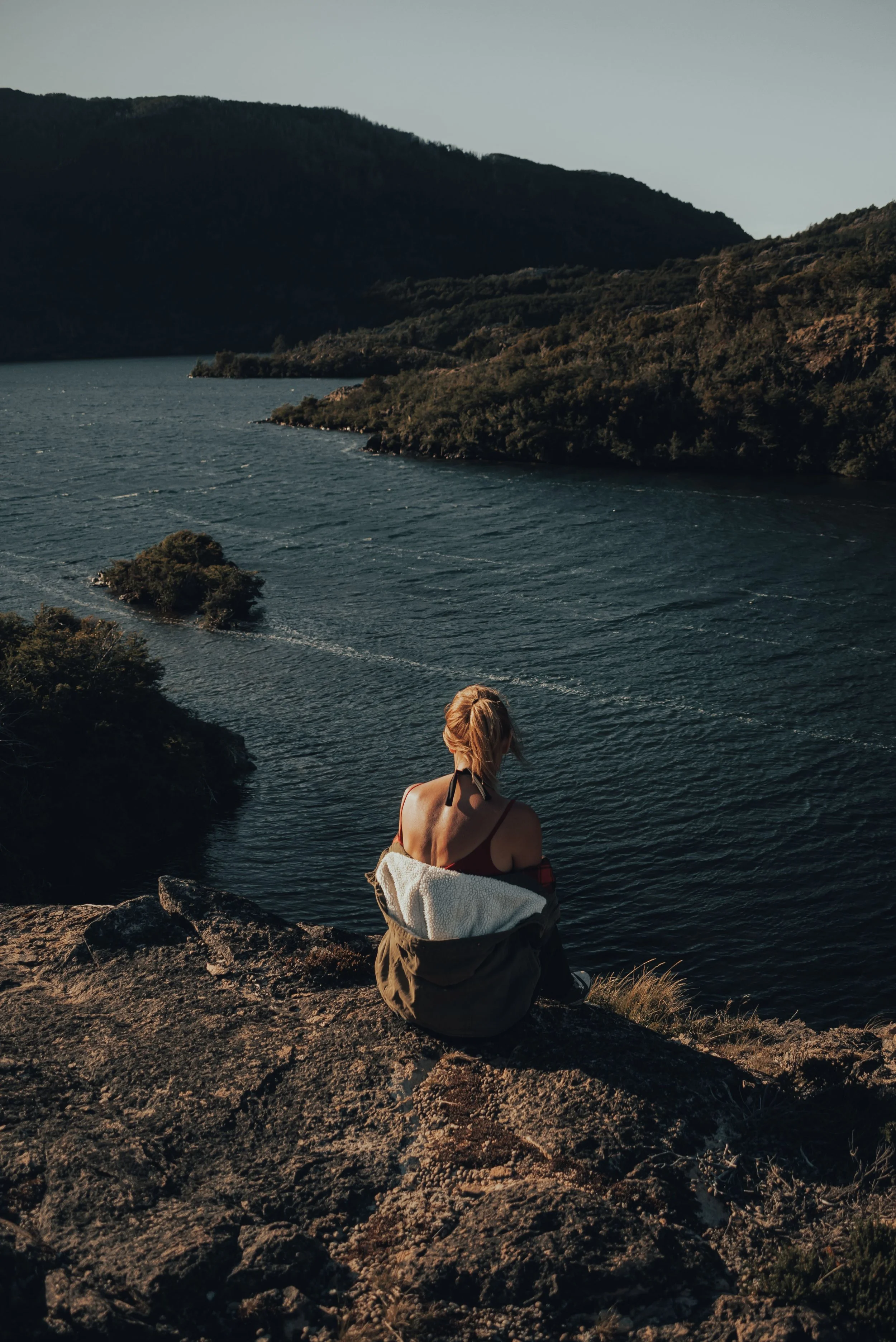 A person sitting quietly on a dock overlooking a calm lake, representing rest, reflection, and mental well-being.