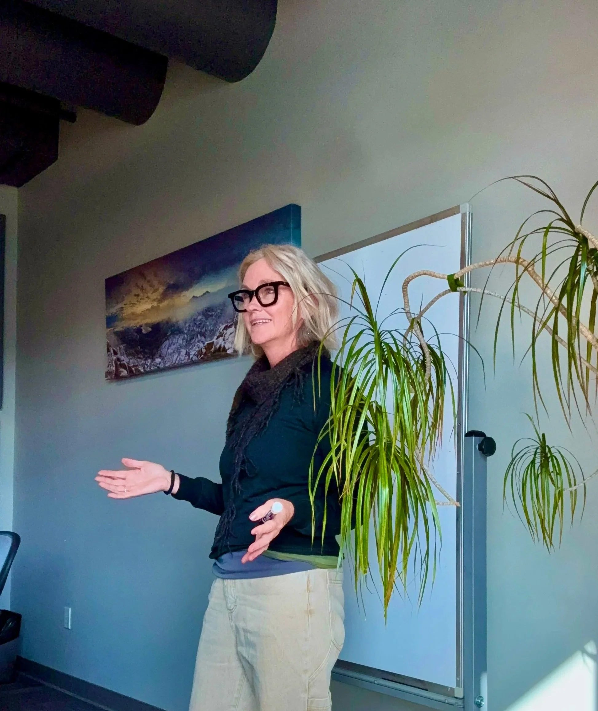 woman standing at a whiteboard gesturing as she's talking