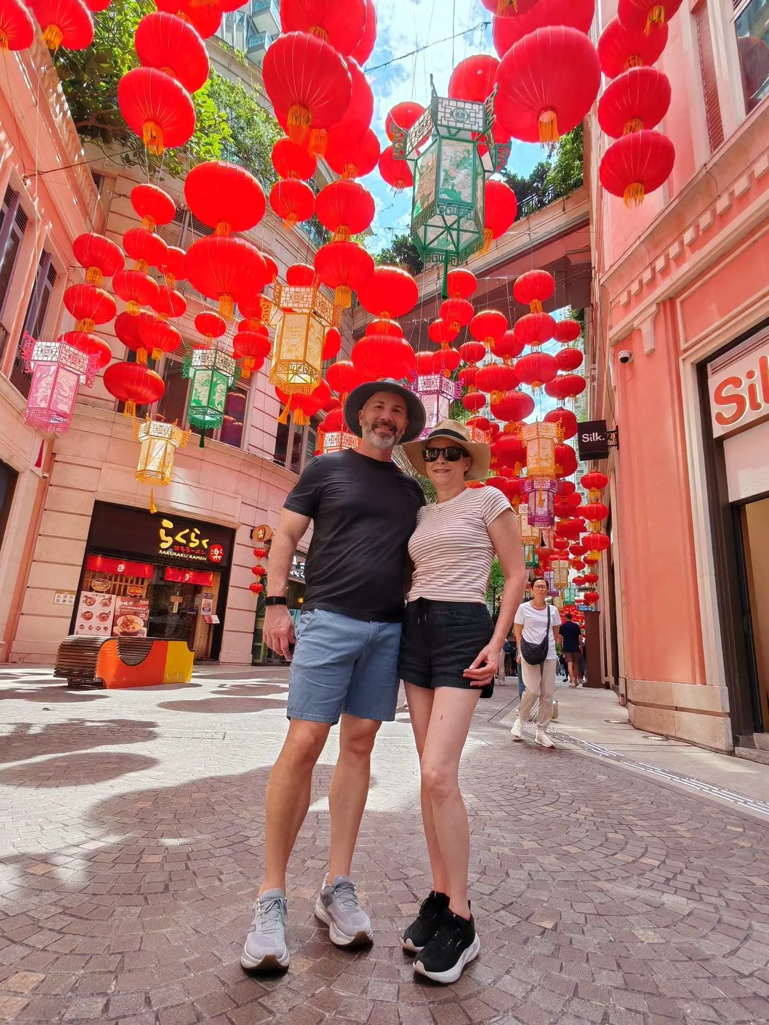 Couple standing beneath rows of red lanterns hanging over a Hong Kong street during Mid-Autumn Festival