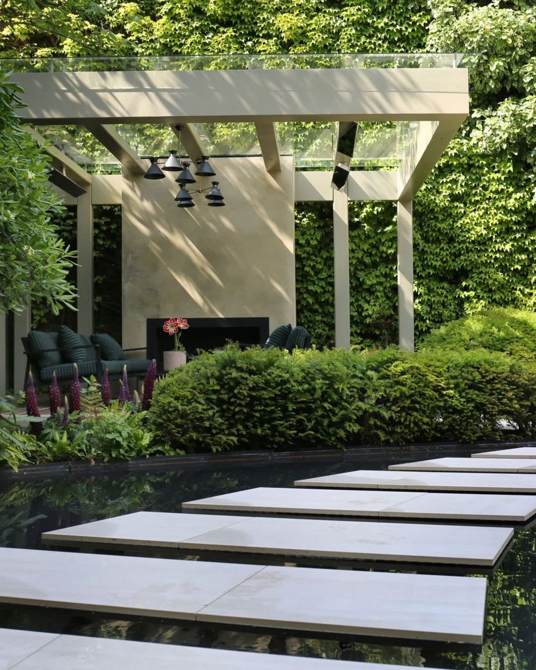 There&rsquo;s something rather magical about morning light in a garden. Here, the sun filters through the canopy of this garden structure, creating a beautiful pattern of light and shadow, also creating a beautiful reflection on water.