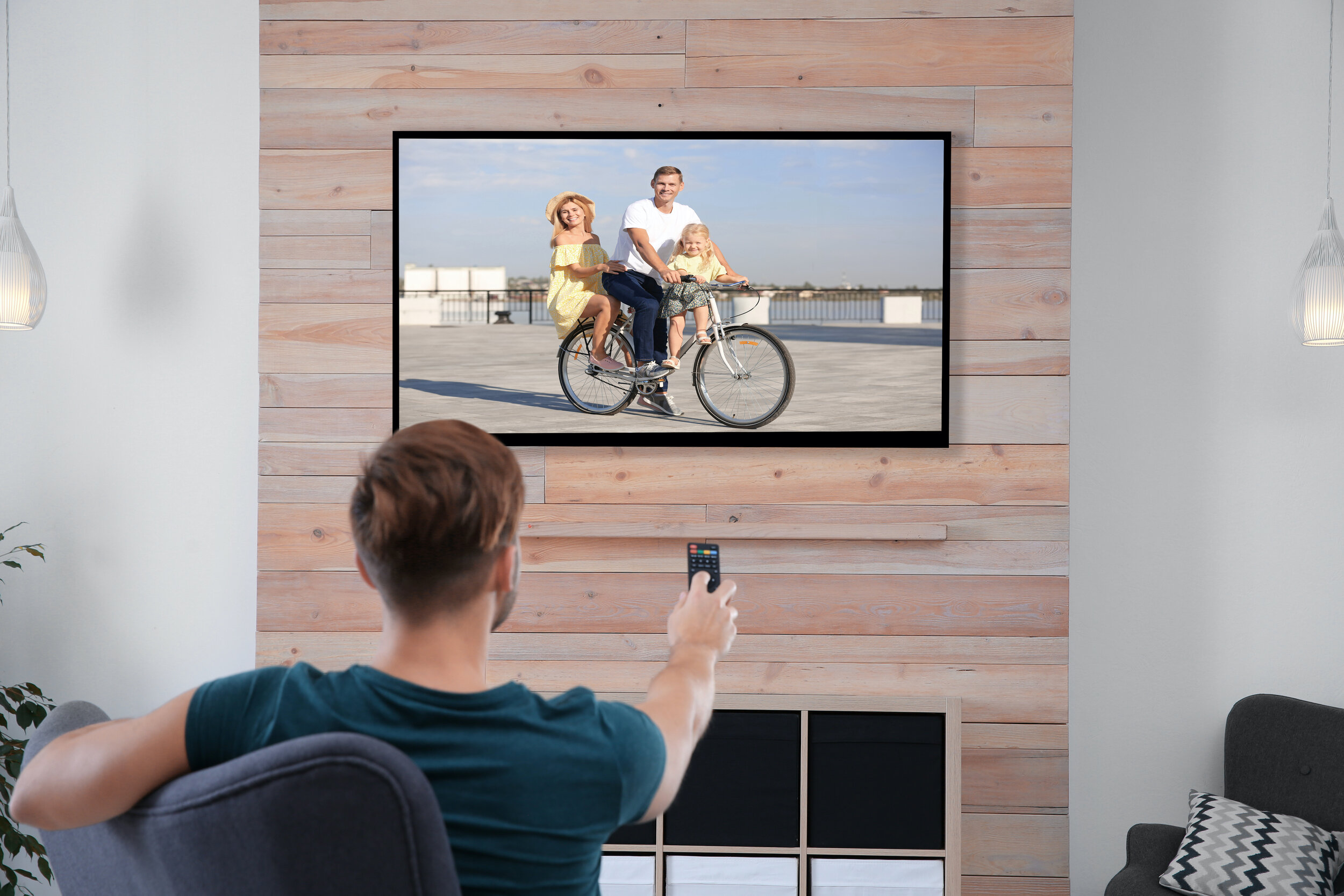 Man sits with remote pointed at TV