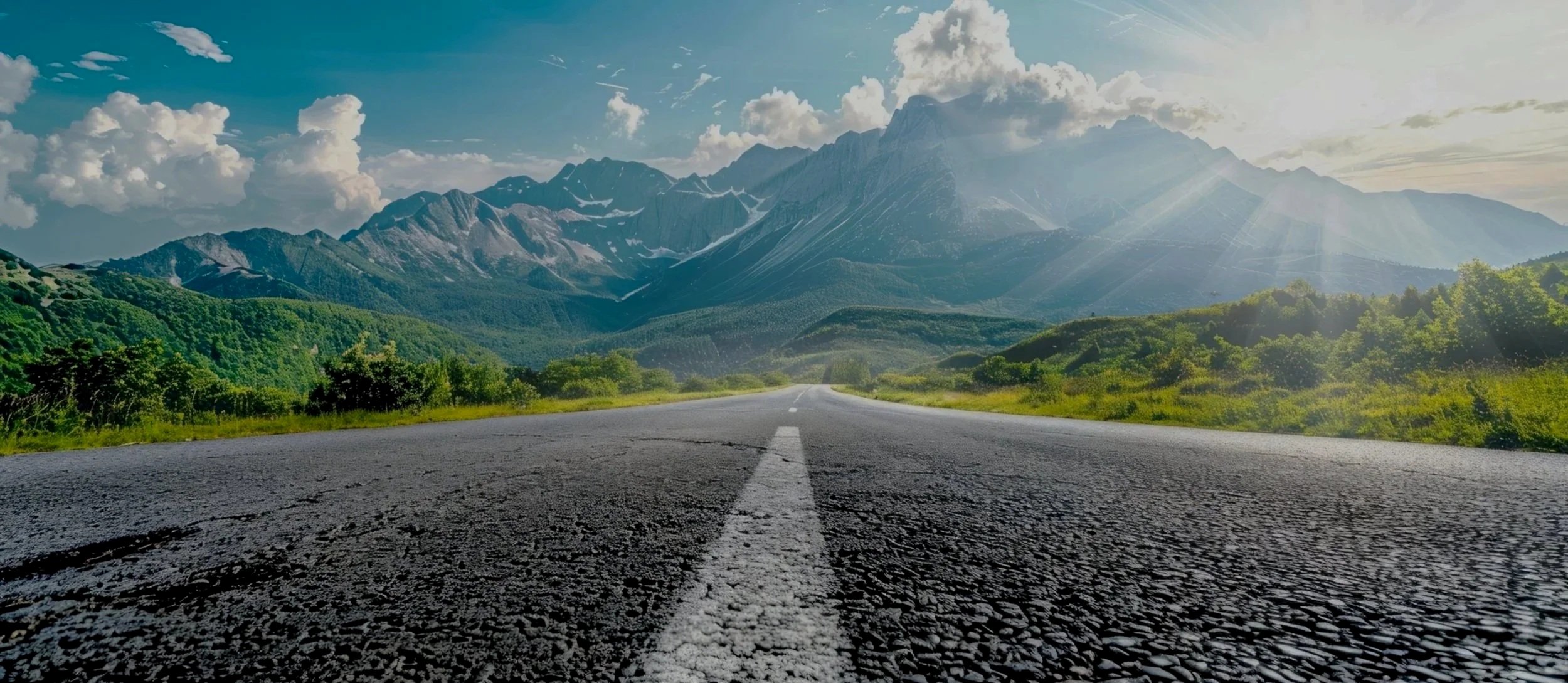 A scenic view of a tree-lined road during autumn, with vibrant orange and yellow leaves, some fallen on the dark asphalt road.