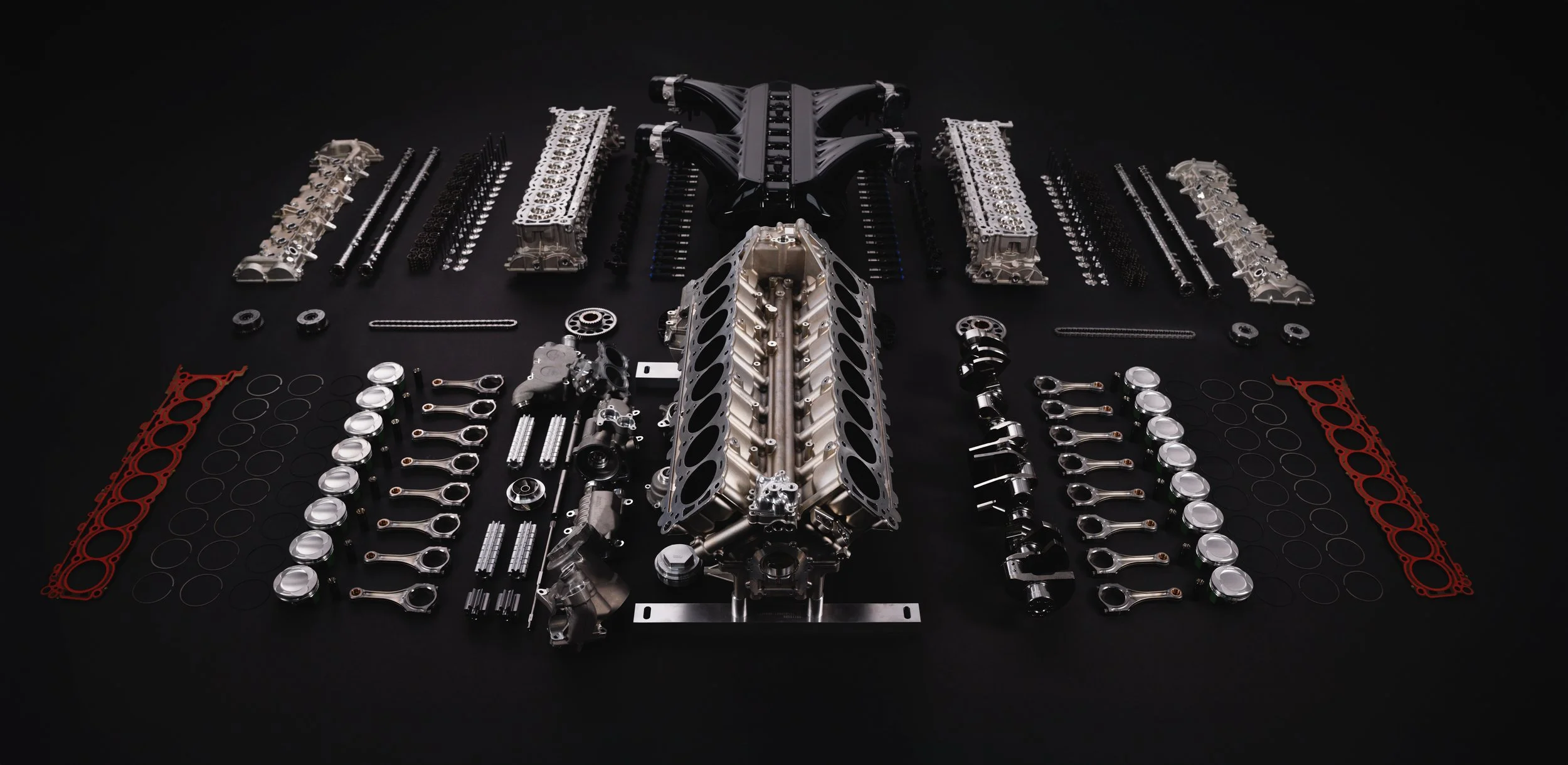 Exploded Bugatti V16 engine with components laid out on black | Anthony Mark Saul