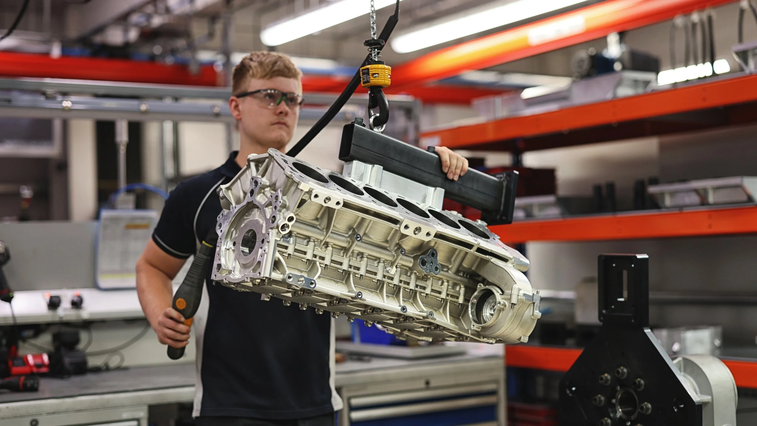 Engineer lifting an engine block on a hoist in a workshop | Anthony Mark Saul