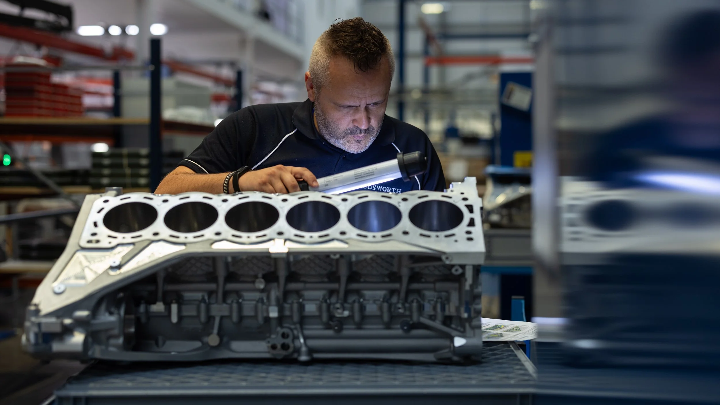 Engineer inspecting a six-cylinder engine block on a workshop bench | Anthony Mark Saul