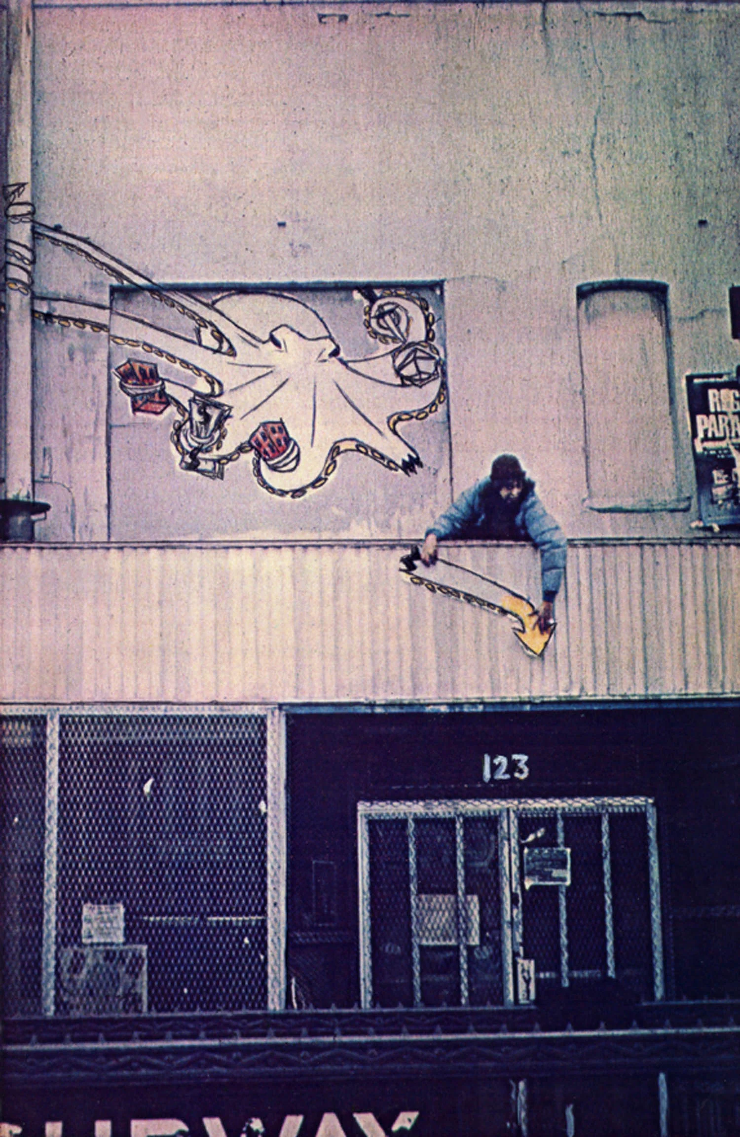 Becky Howland affixes painted paper octopus to the front of 125 Dlancey Street. Photo by Ann Messner