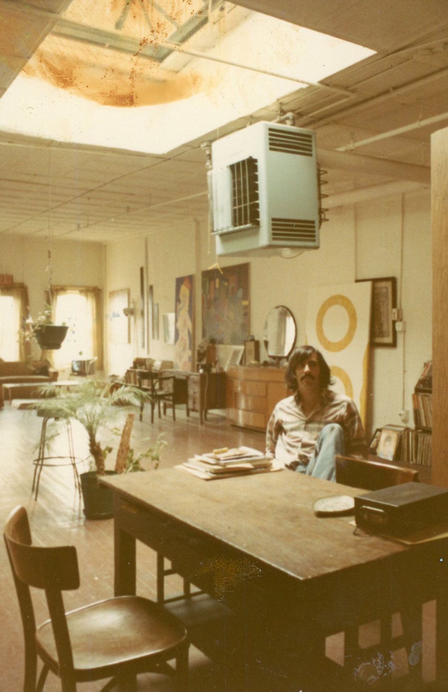 Marc at the dining room table with Tom Wolf's painting behind him, c. 1972.