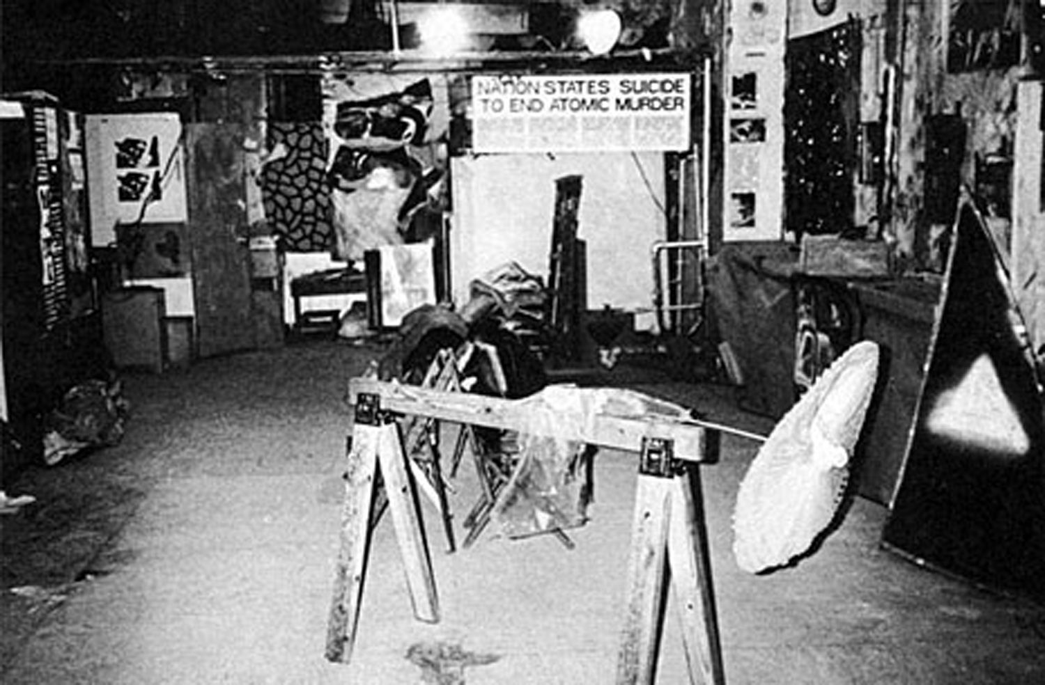 Installation view looking north and showing sawhorse sculpture by Richard VanBuren in foreground, and at rear Nation States Suicide to End Atomic Murder , a statement by Peter Fend. Photo by Tom Warren